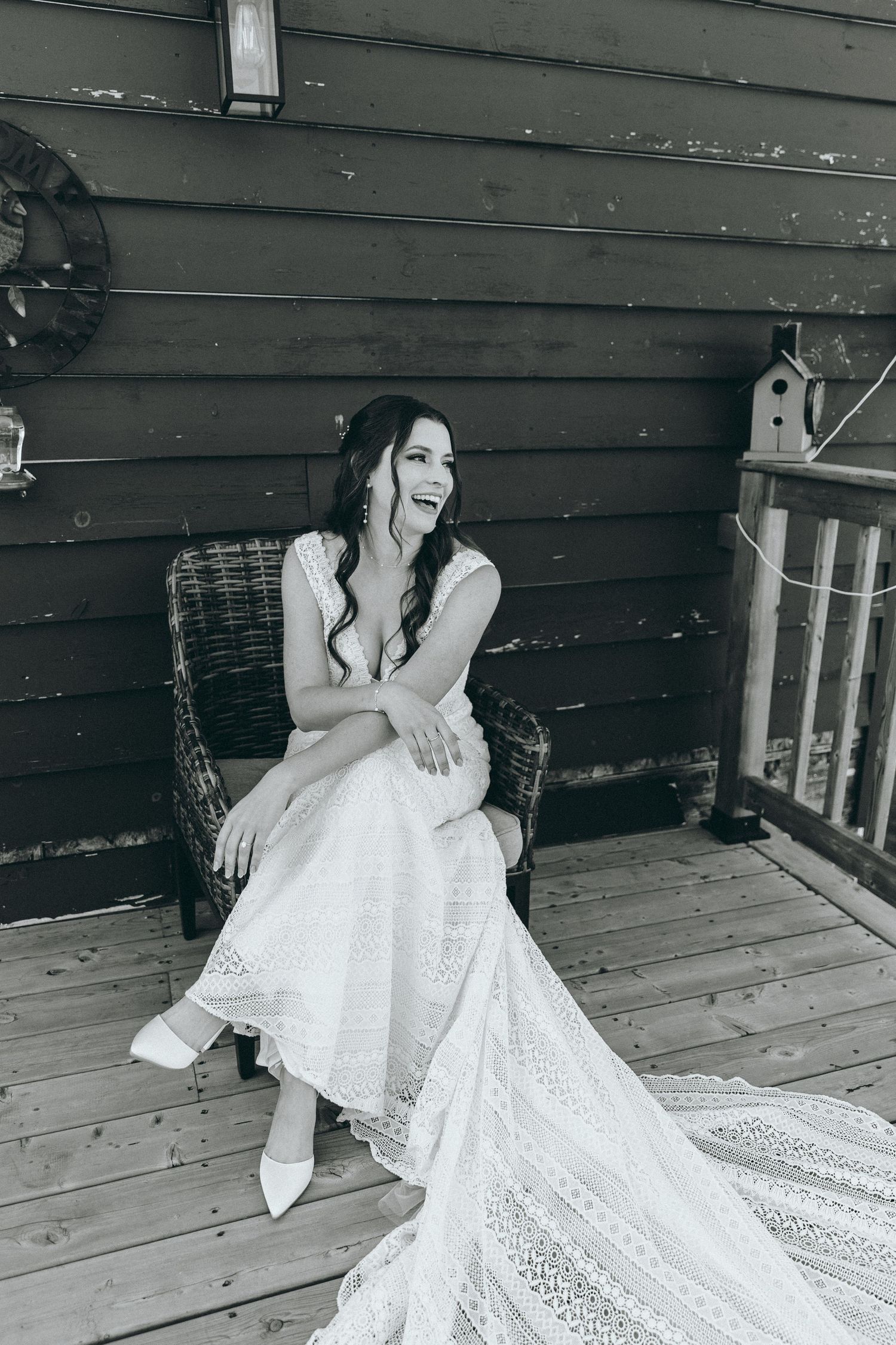 A flowing white lace wedding dress displayed on a rustic wooden porch.