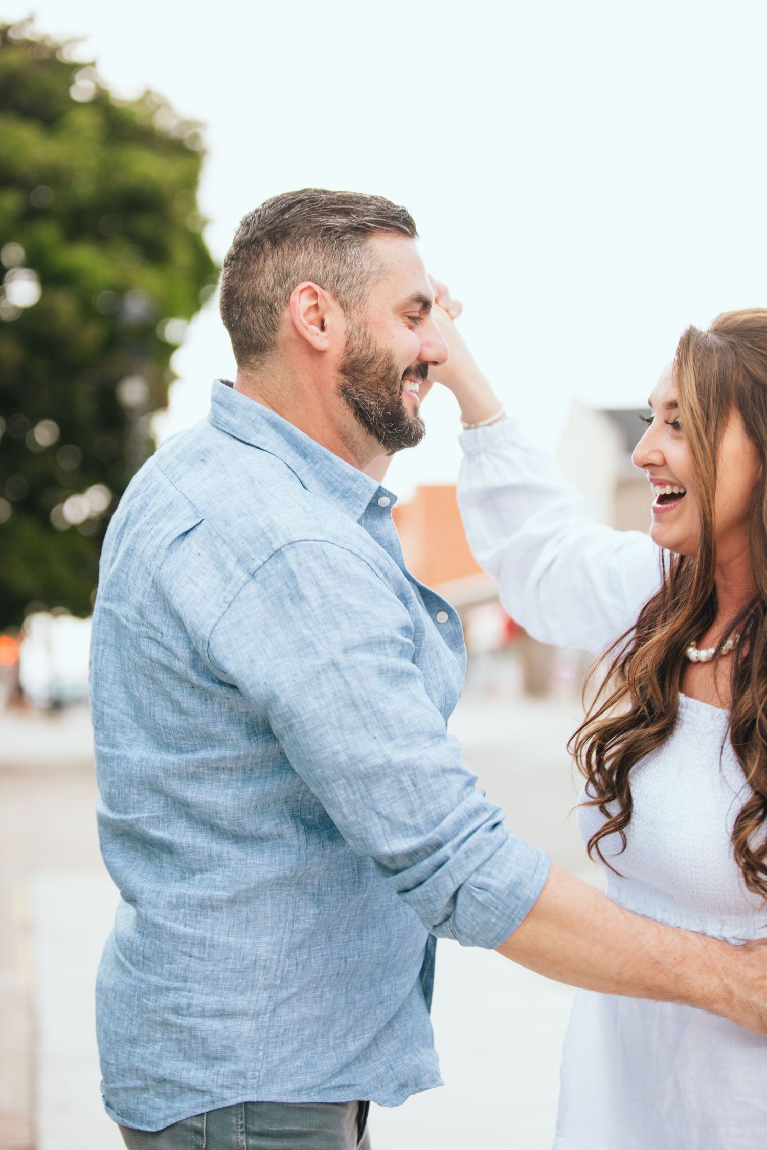 Playful couple laughing and dancing together outdoors.