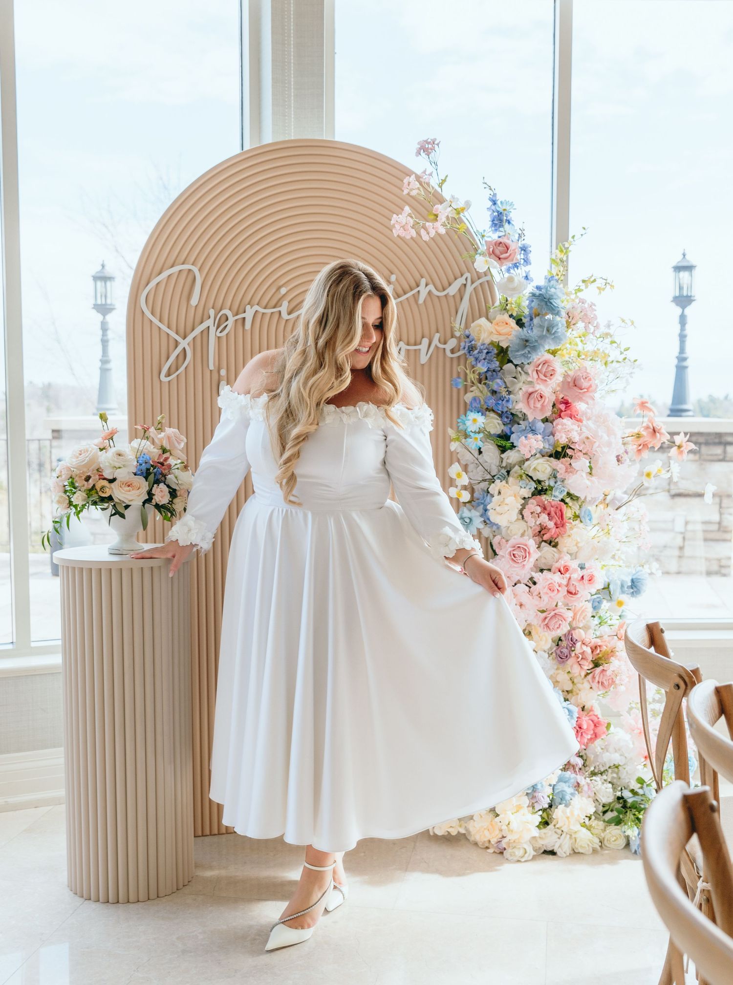 White dress twirling in an elegant setting with floral decorations and arched panels.