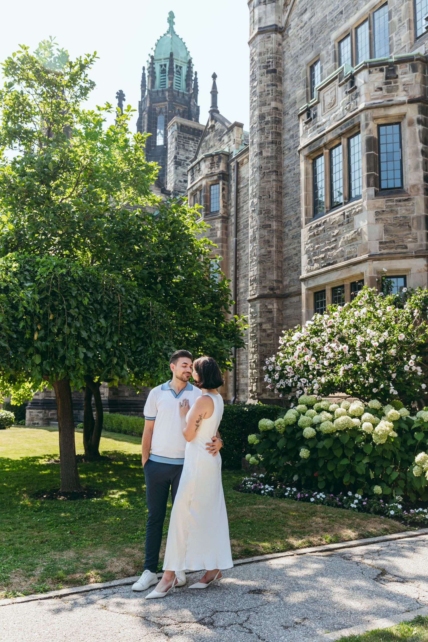 A couple shares a tender moment on the grounds of a beautiful stone cathedral.