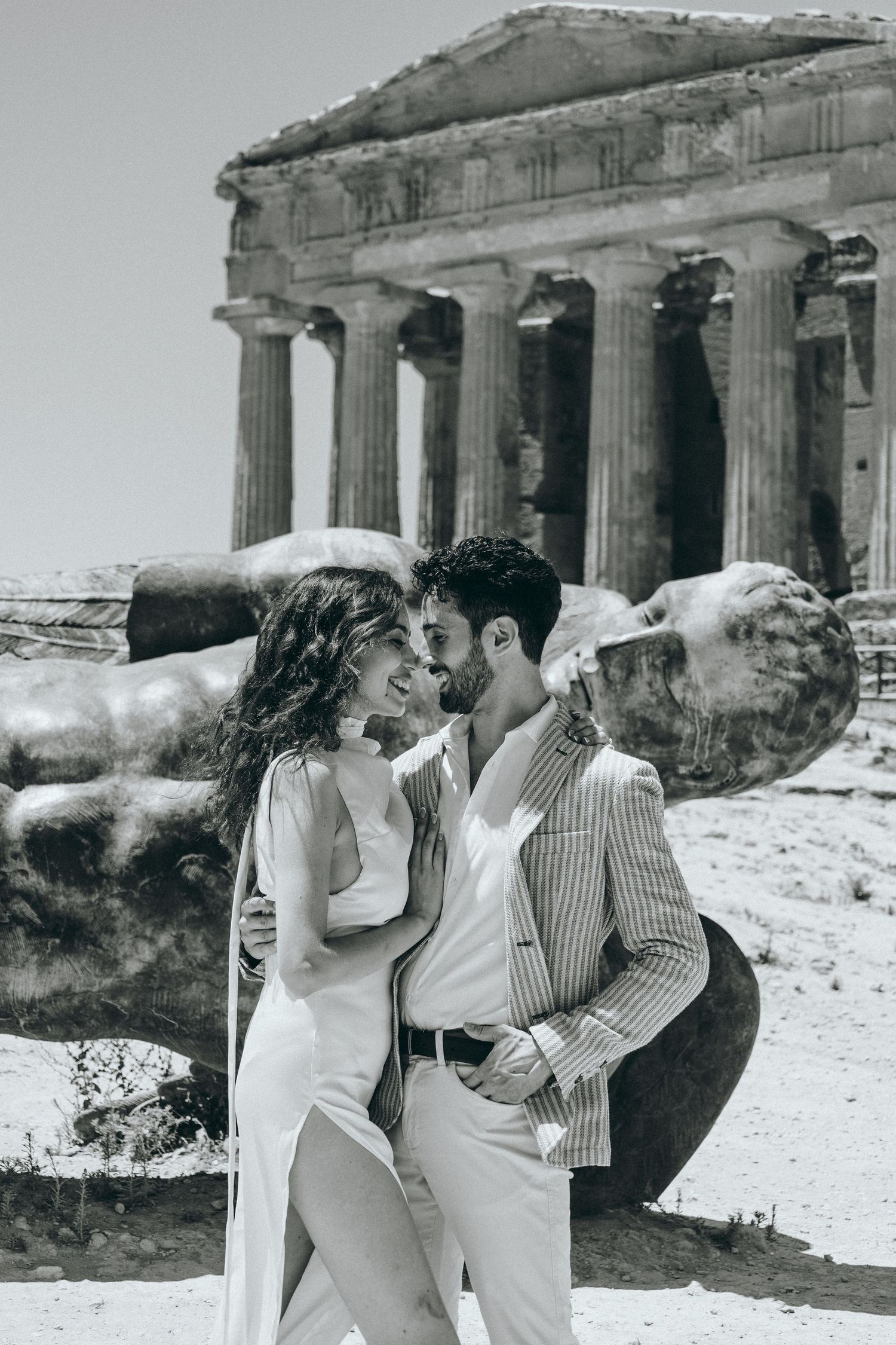 A couple poses romantically in front of ancient Greek temple columns in Sicily.