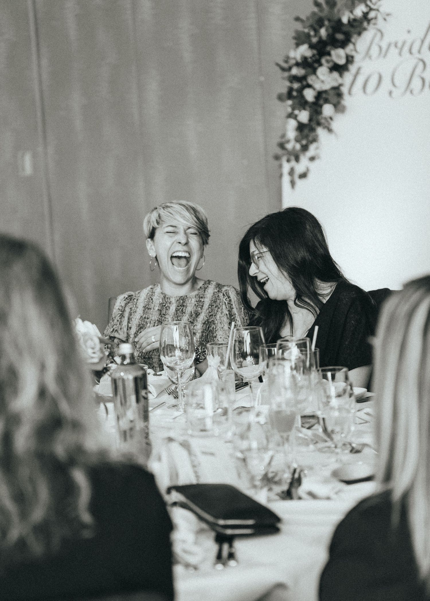 Black and white photo of lively reception dinner with decorated tables.