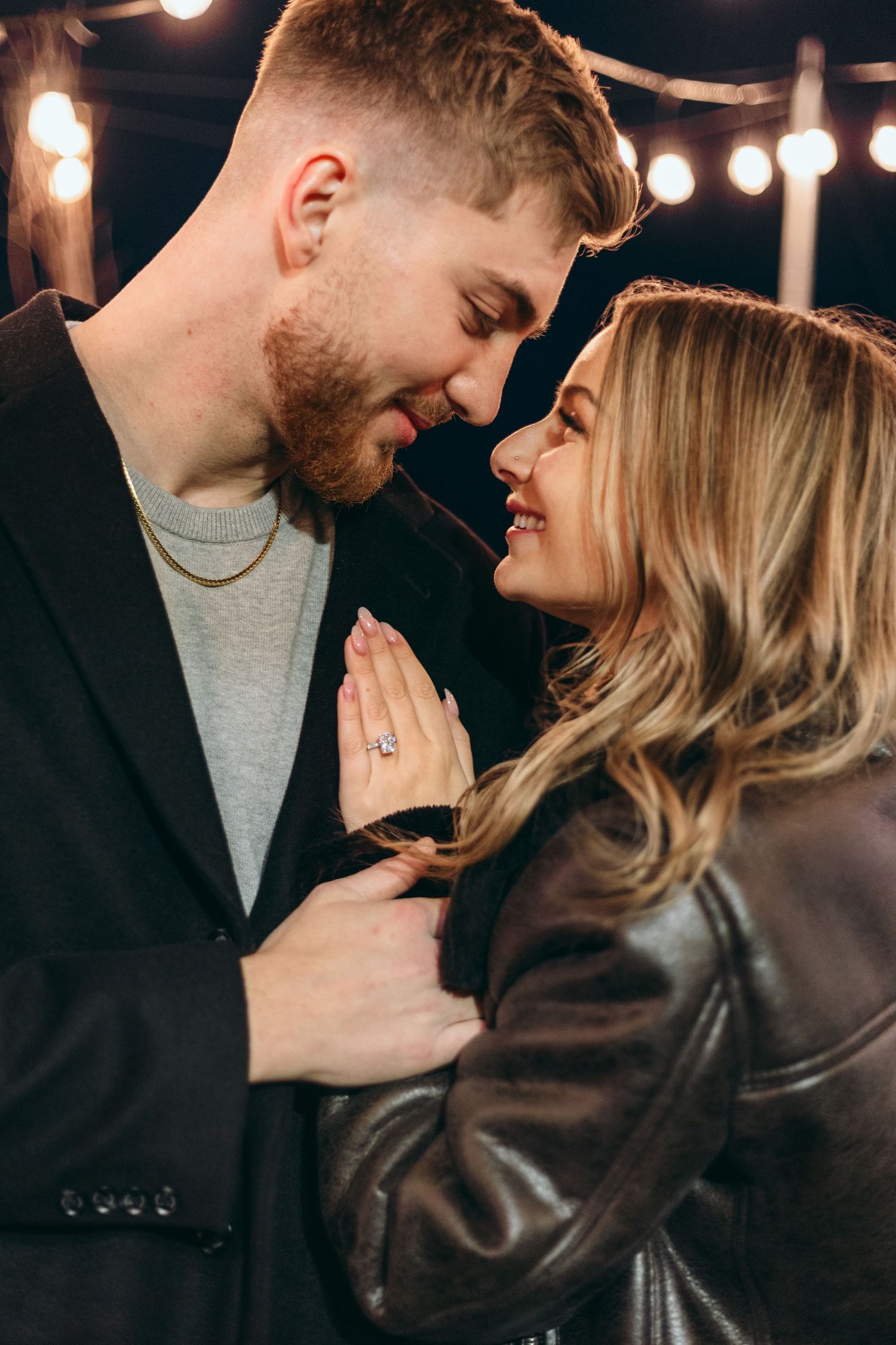 Intimate couple portrait with string lights in background showing tender moment.