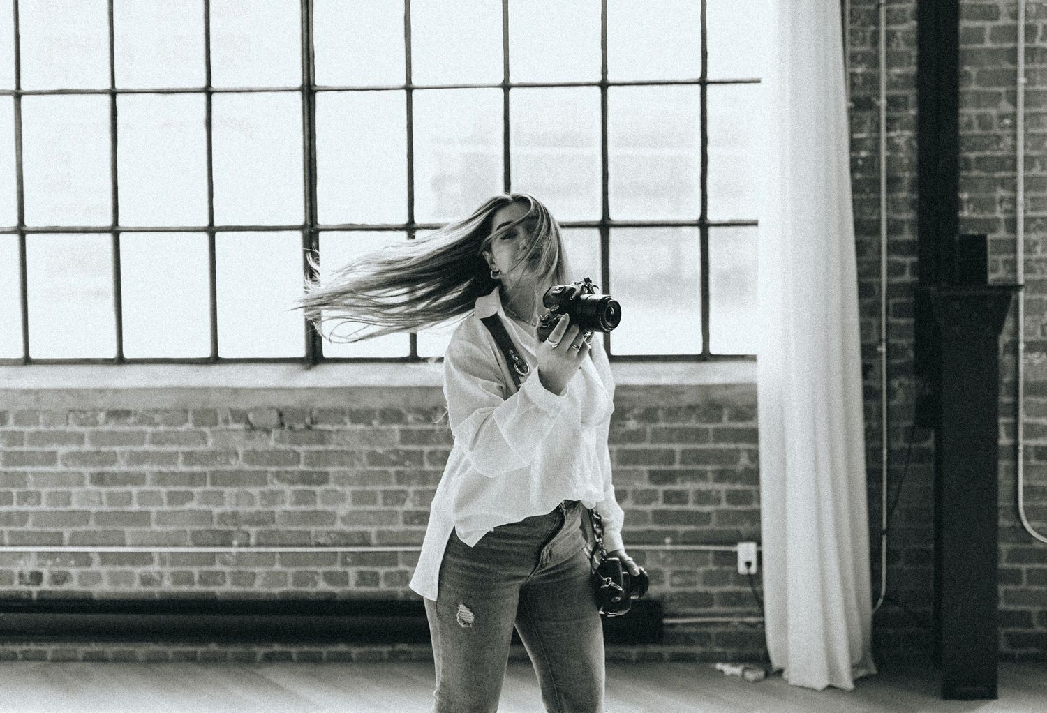 Black and white photo of dancers in an industrial loft space with large windows.