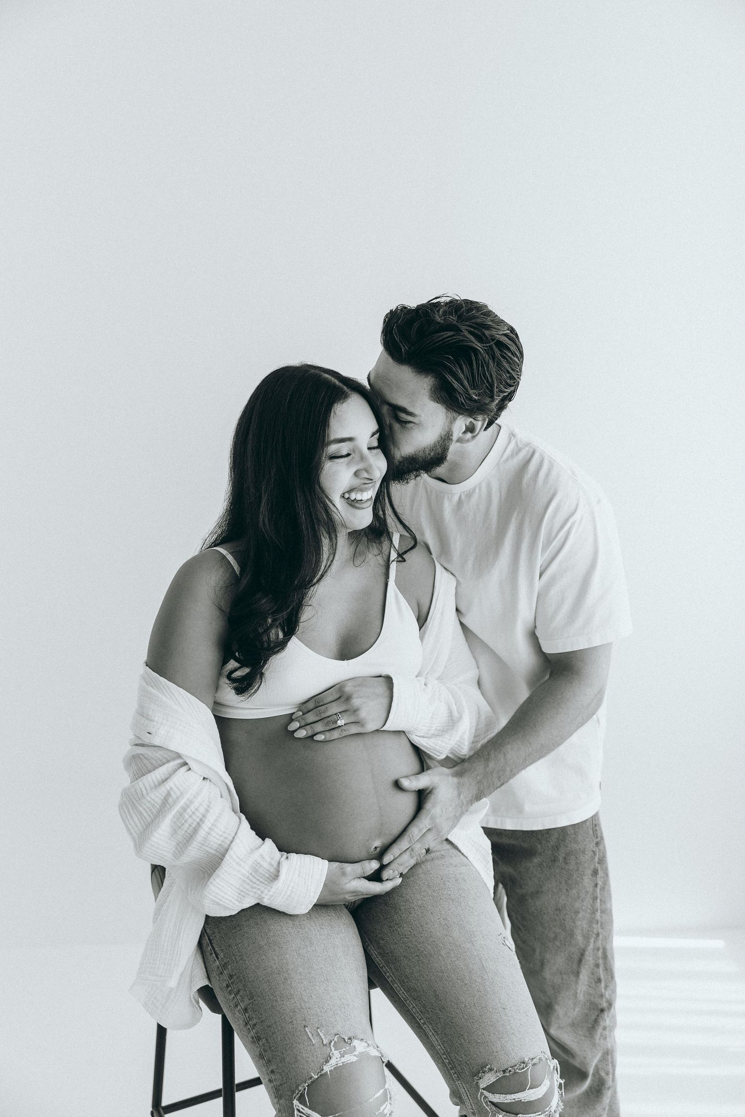 A joyful couple shares laughter during an intimate black and white photoshoot.