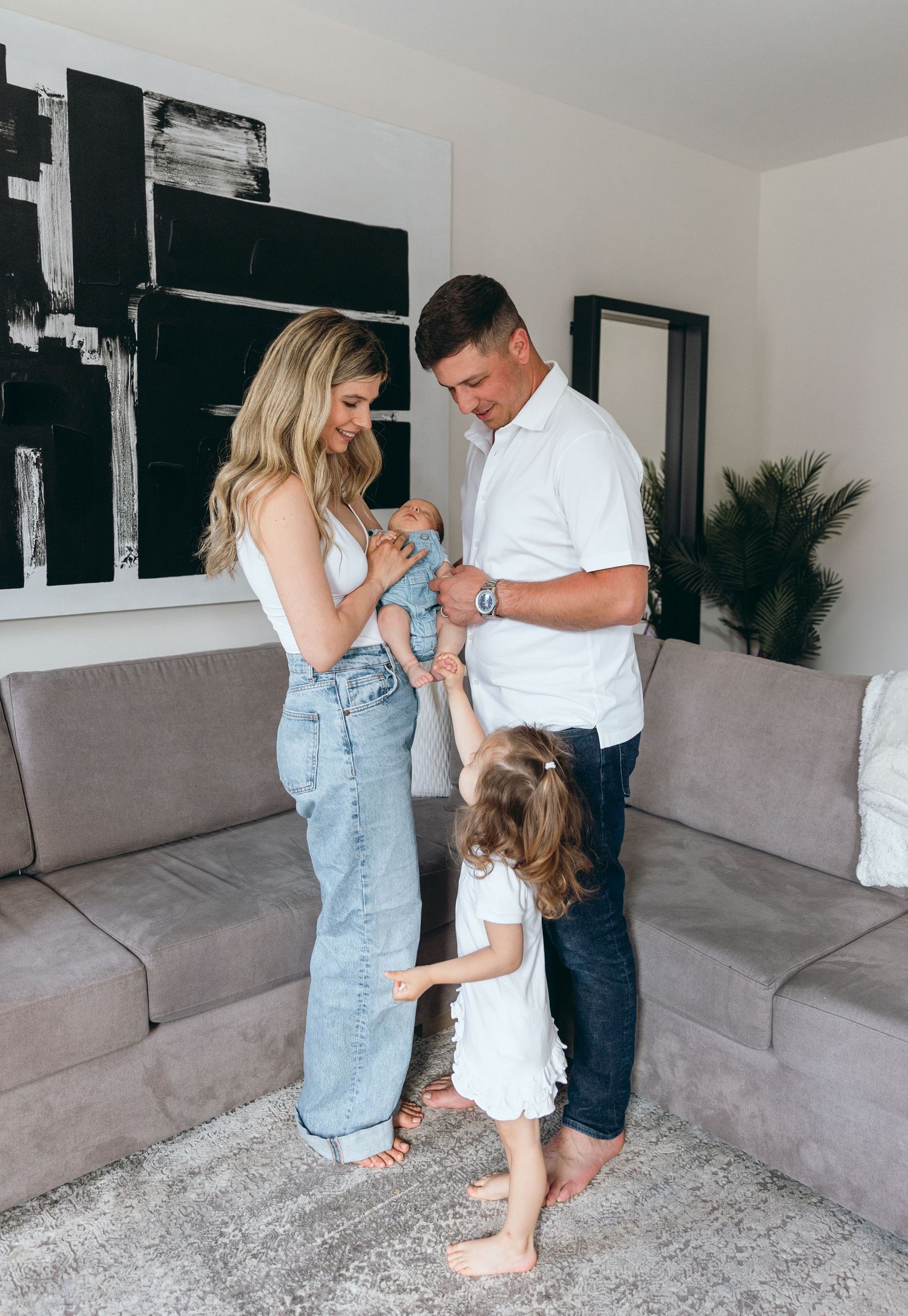 A family shares playful moments together in their living room with a gray couch.
