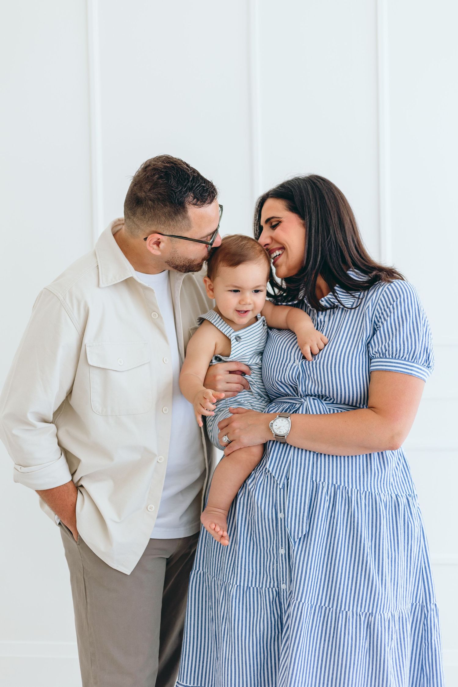 Intimate family portrait against white background in casual coordinated outfits.