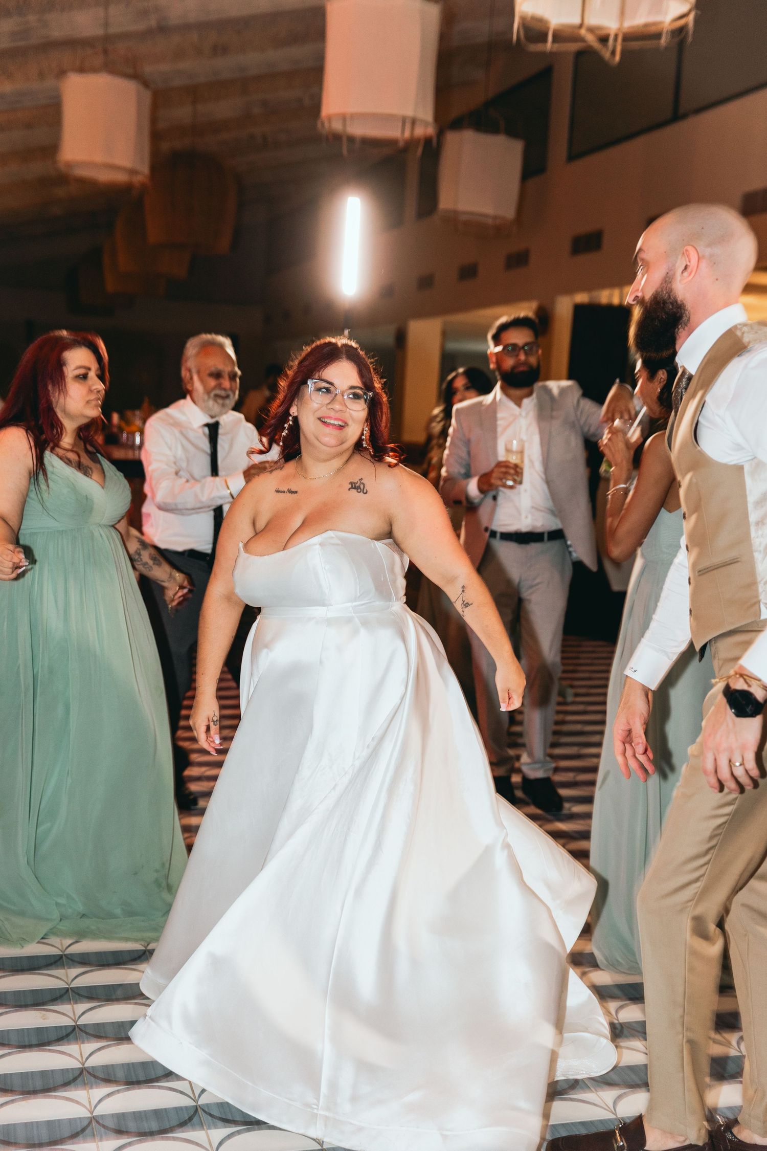 A person in a white wedding dress dances during reception celebrations.