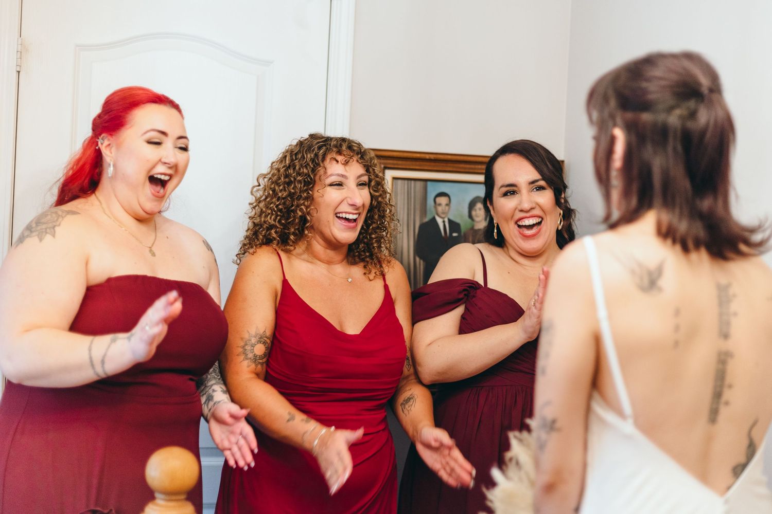 Wedding party in burgundy dresses reacting with joy and excitement.