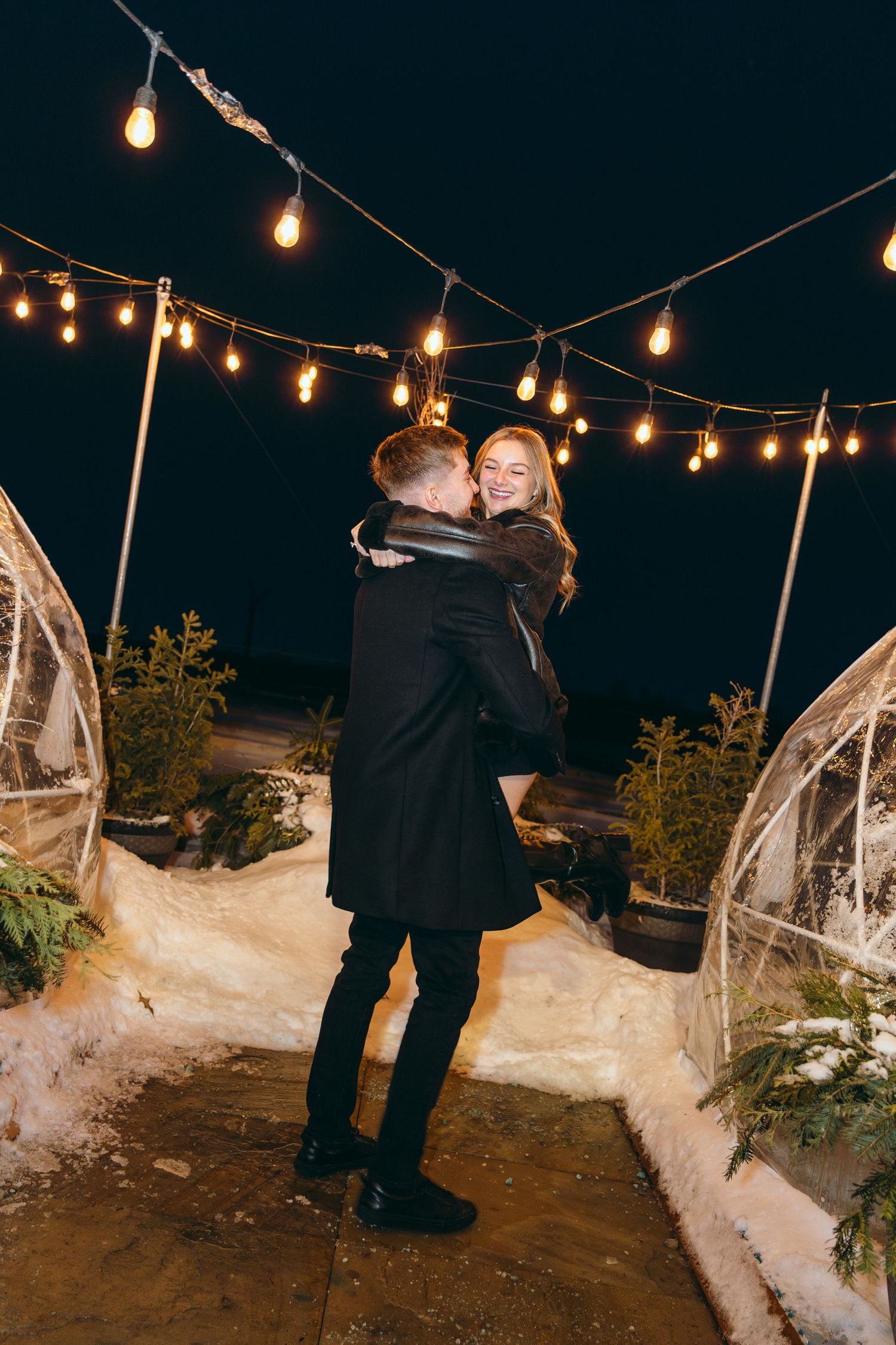Romantic nighttime scene with string lights and snow-covered ground.