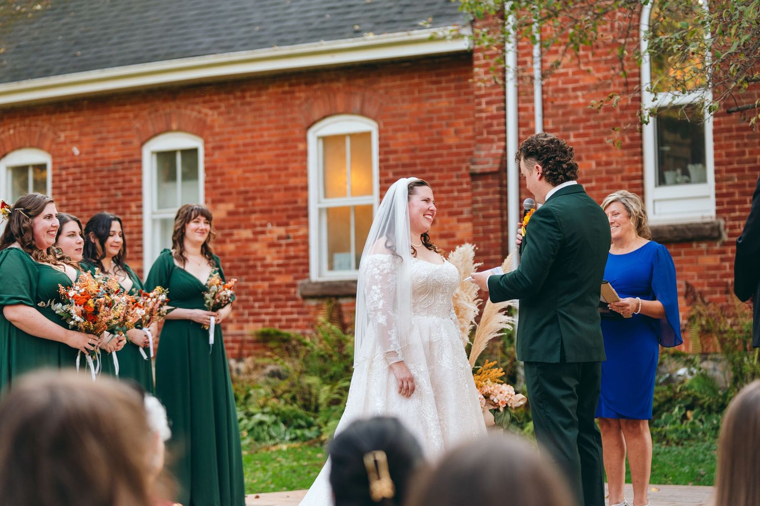 Wedding ceremony guests gather outside brick building during fall season.