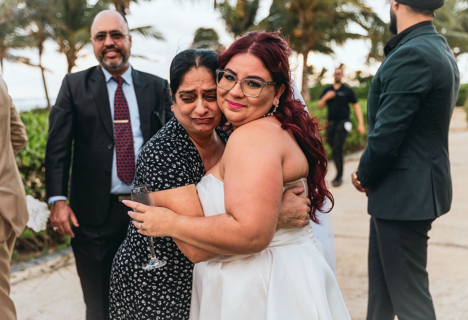 Wedding reception guests dance and mingle at an outdoor tropical venue.
