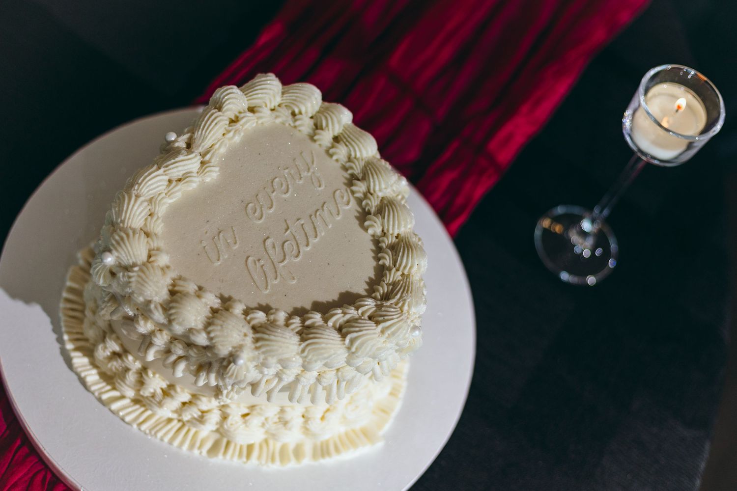 White wedding cake with delicate piped details and pearl decorations on display.