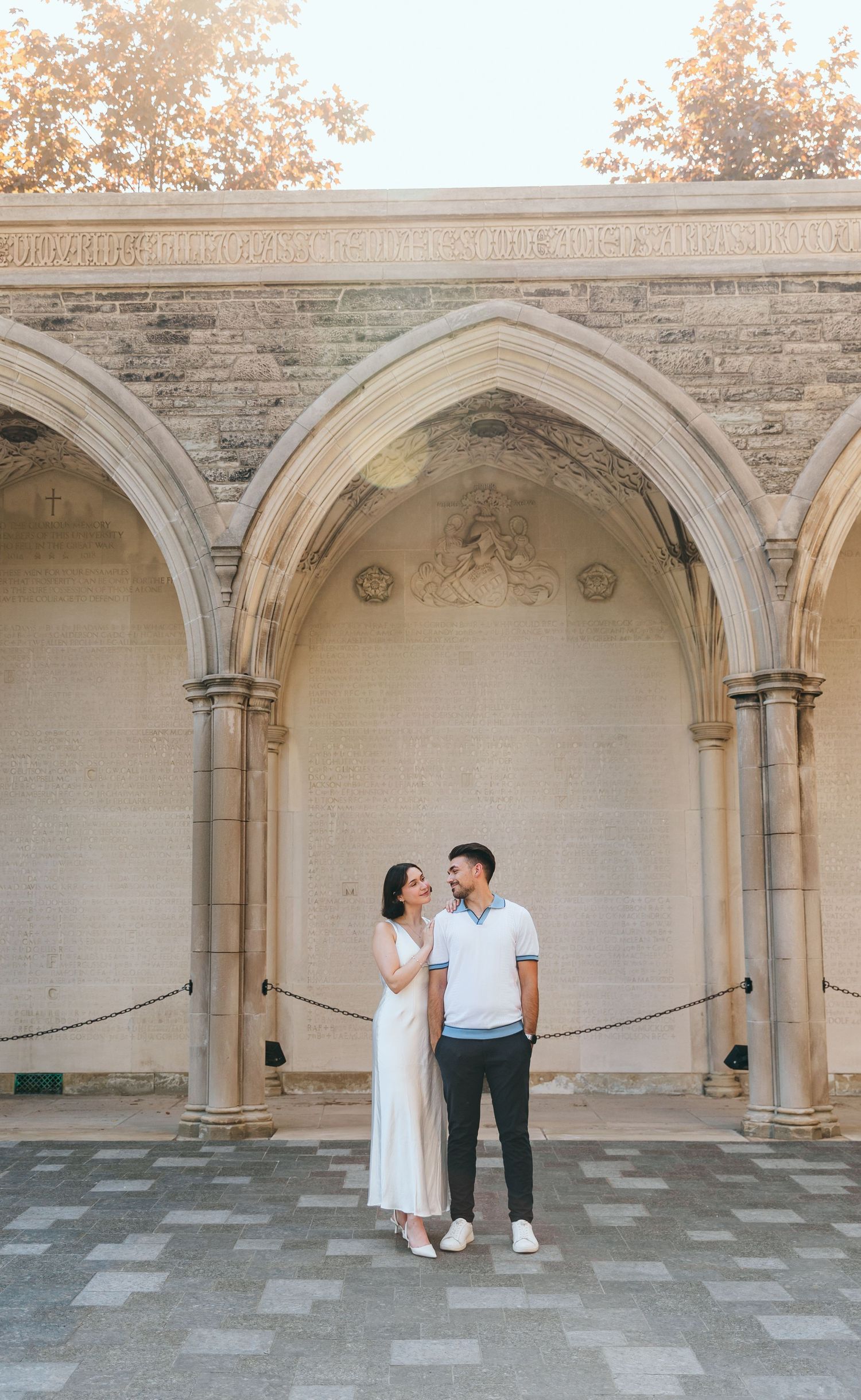 A couple shares an intimate moment beneath historic Gothic architecture.