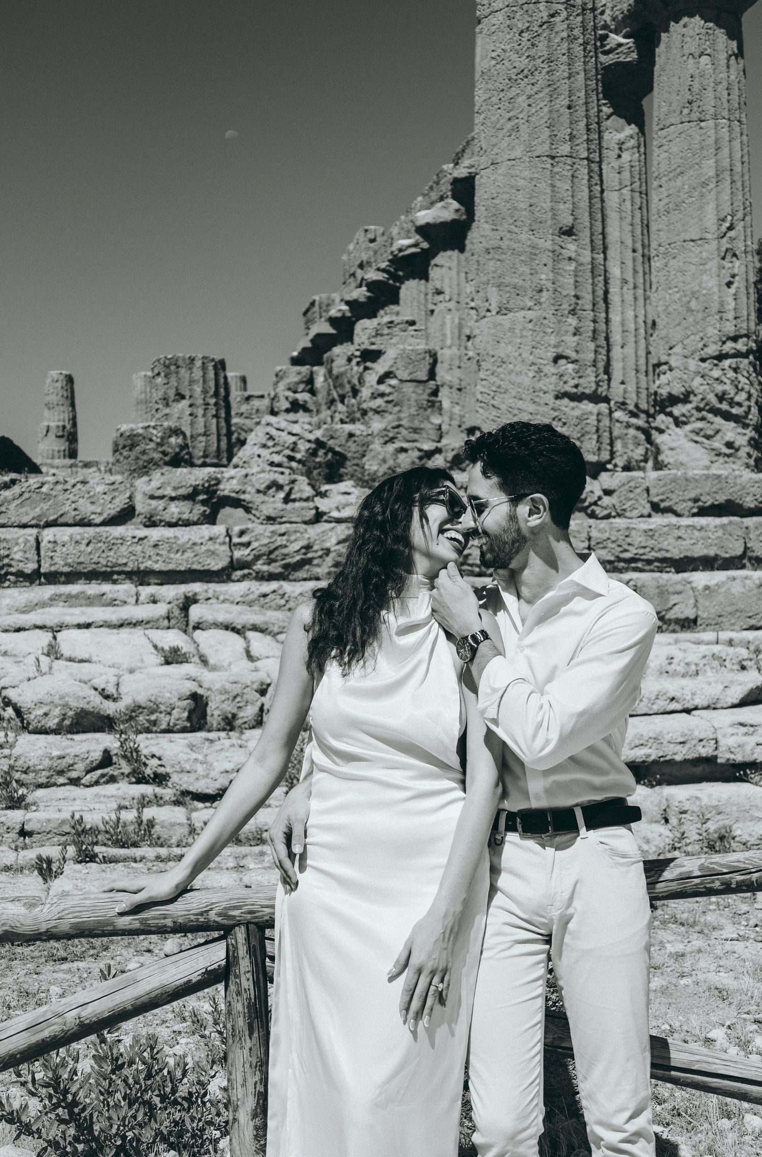 Black and white romantic portrait of couple at ancient Greek temple ruins.