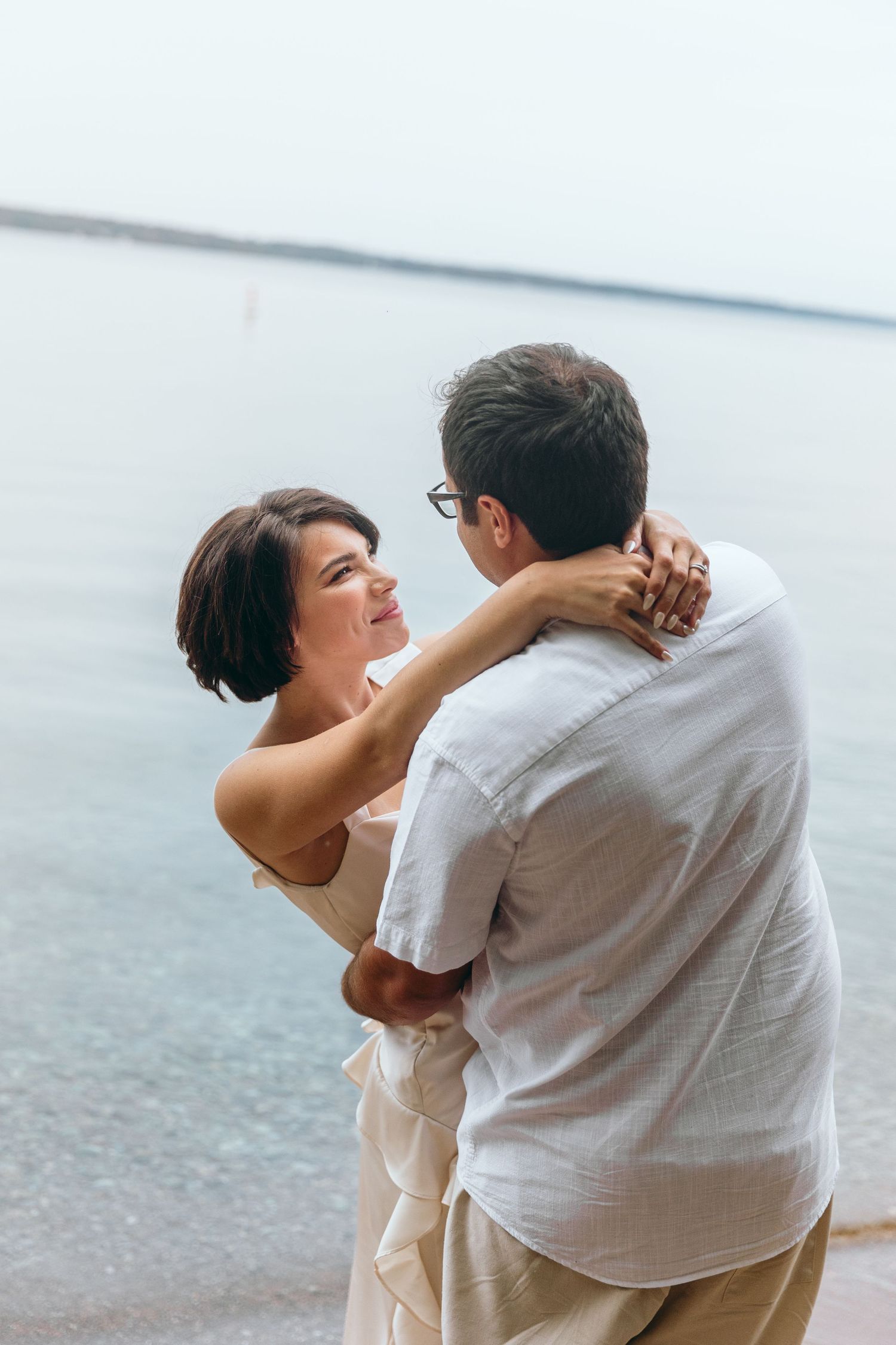 Romantic embrace between couple on waterfront in casual attire.