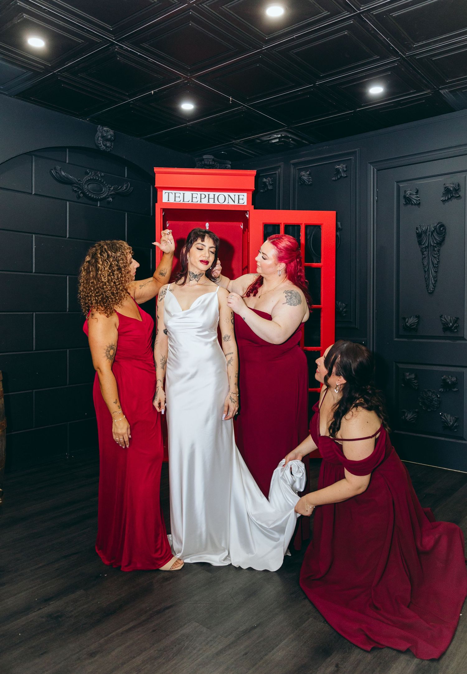Wedding party poses dramatically in dark room with red accents.