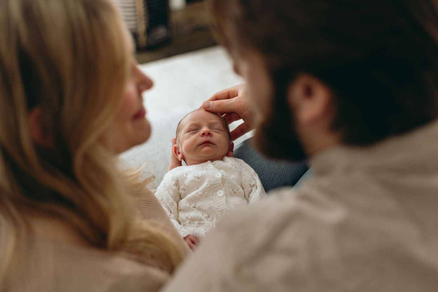 Intimate lifestyle photos of parents bonding with their newborn on a light background.