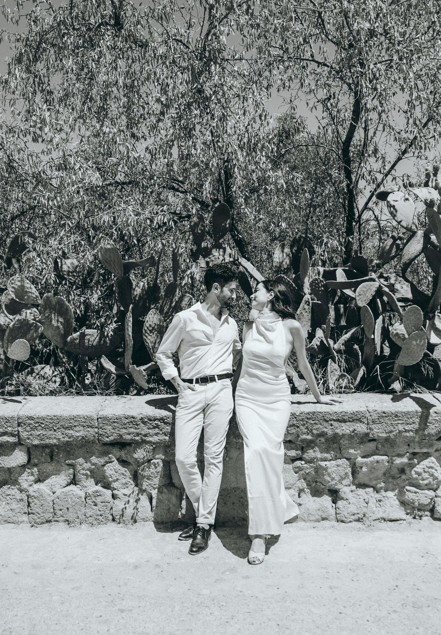 A couple shares a joyful moment together while sitting on a rustic stone wall.