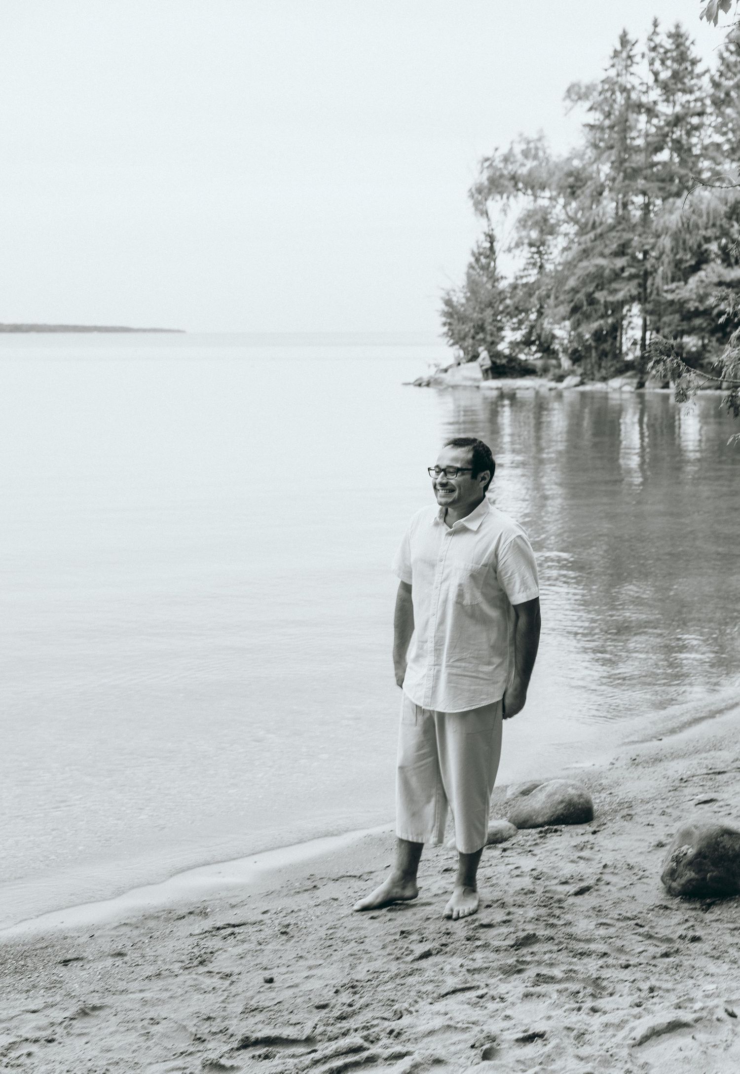 A solitary figure standing on a peaceful beach looking out at the water.