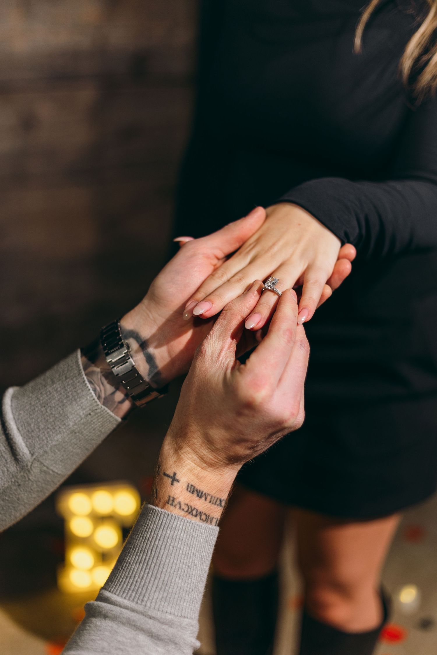 Close-up of hands during a marriage proposal with a ring being placed on finger.