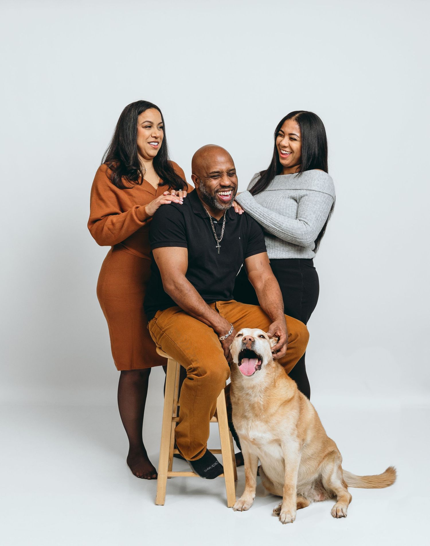 Studio photoshoot of family with golden retriever dog on white background.