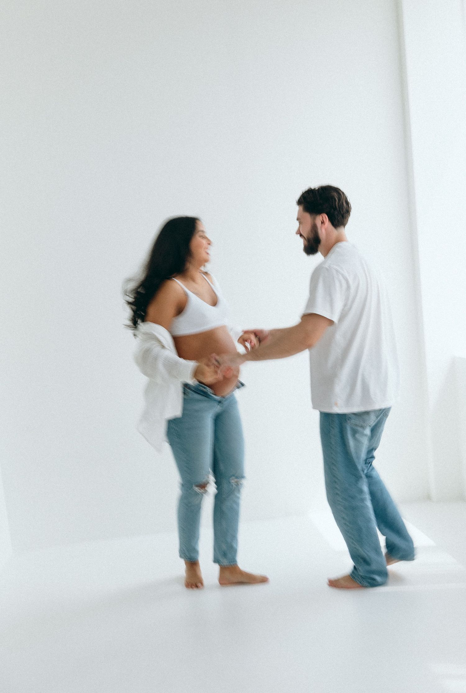 Playful maternity poses captured in bright white studio space.