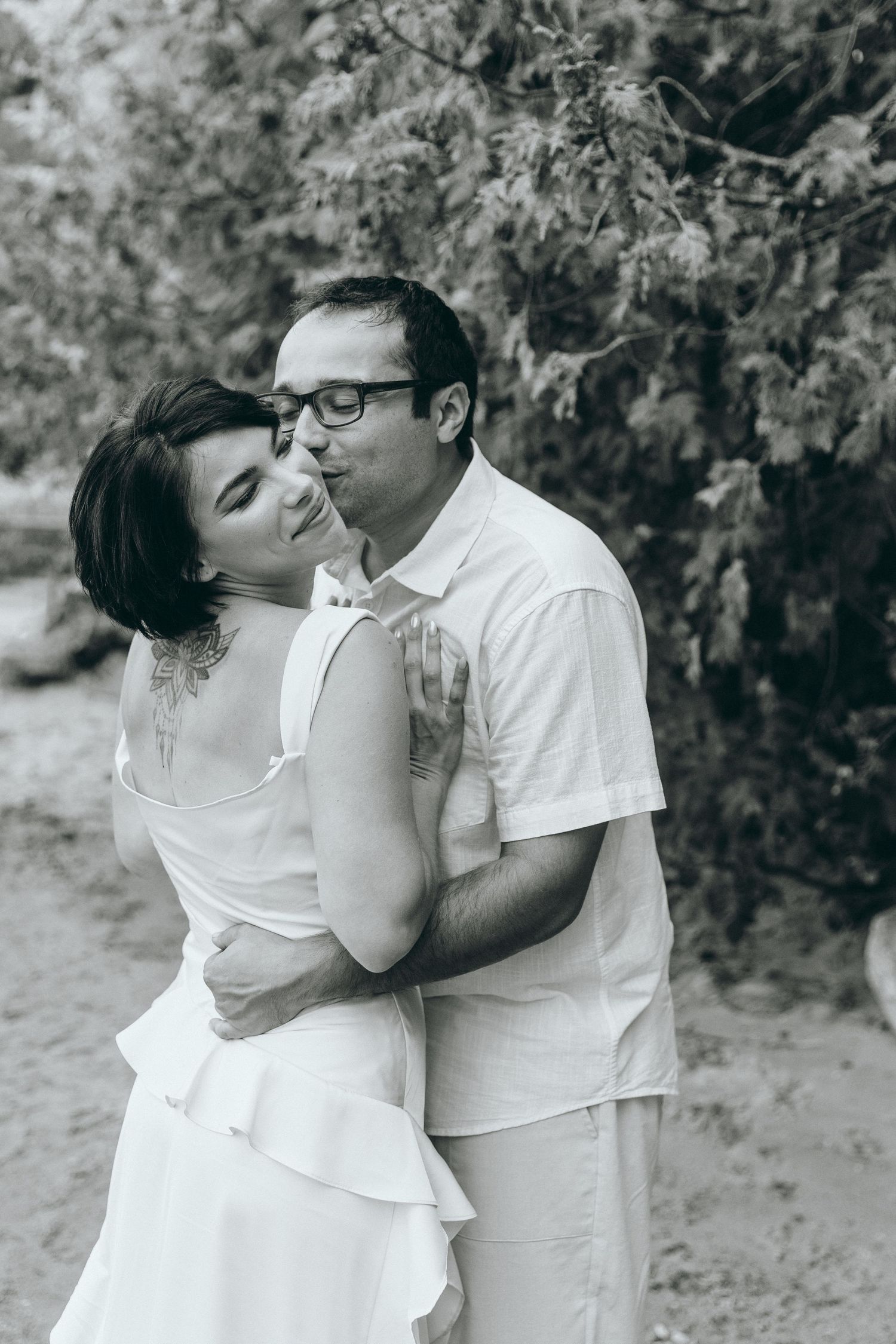 A romantic moment shared between two people dressed in white against a natural backdrop.