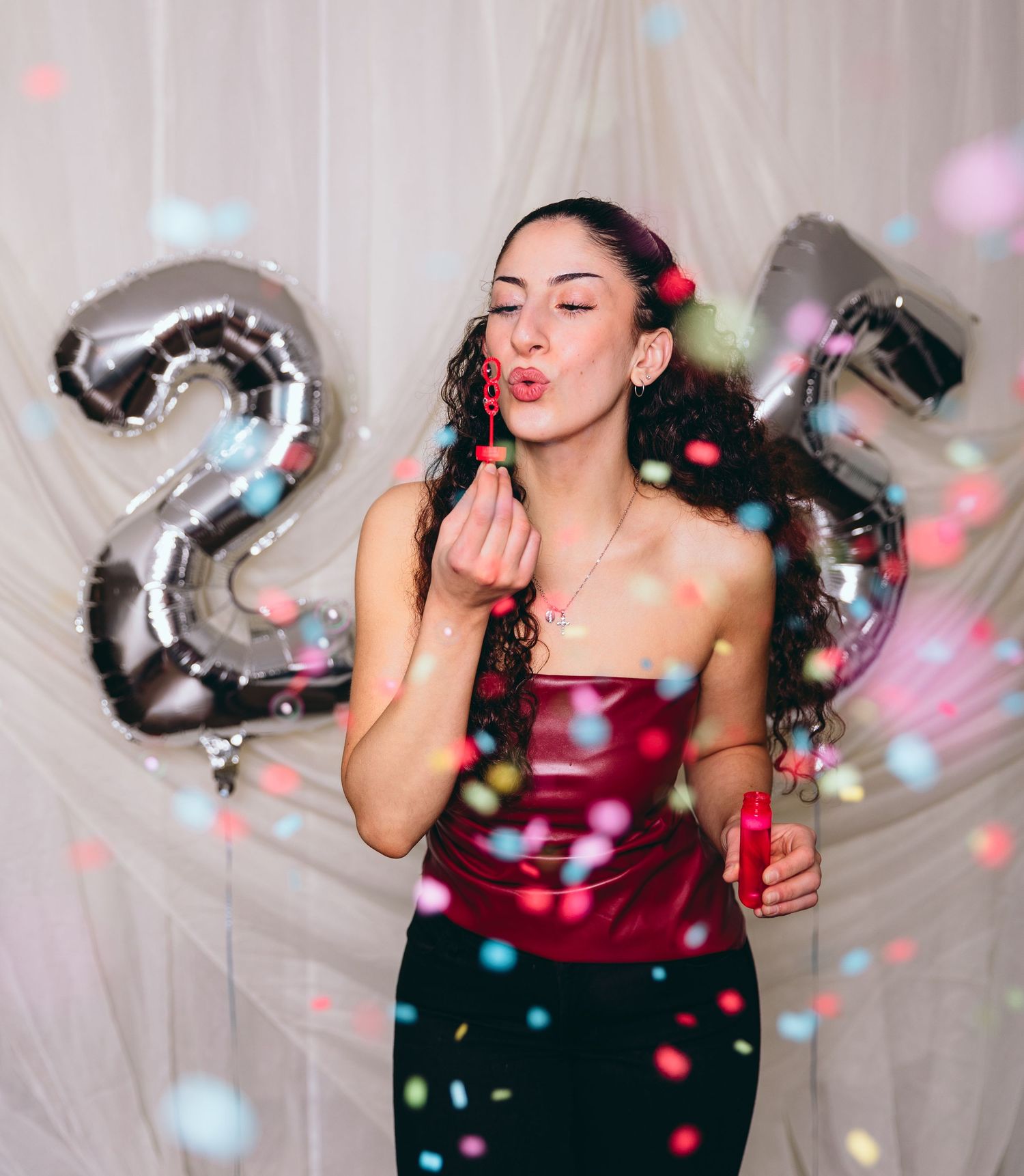 Celebratory scene with confetti and silver number balloons against white backdrop.