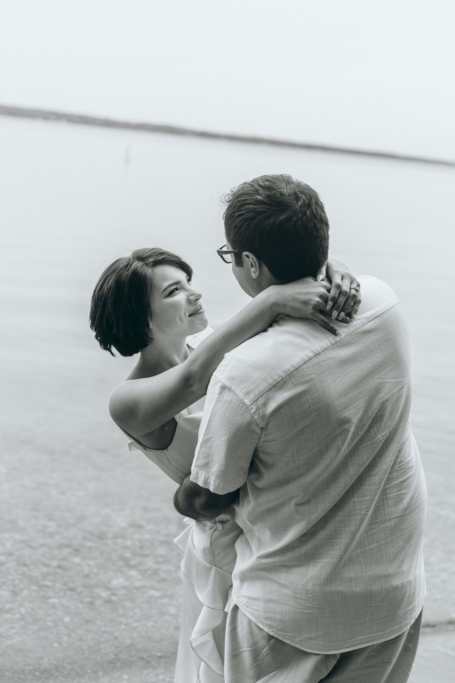 A tender moment captured between two people in white clothing against a bright background.