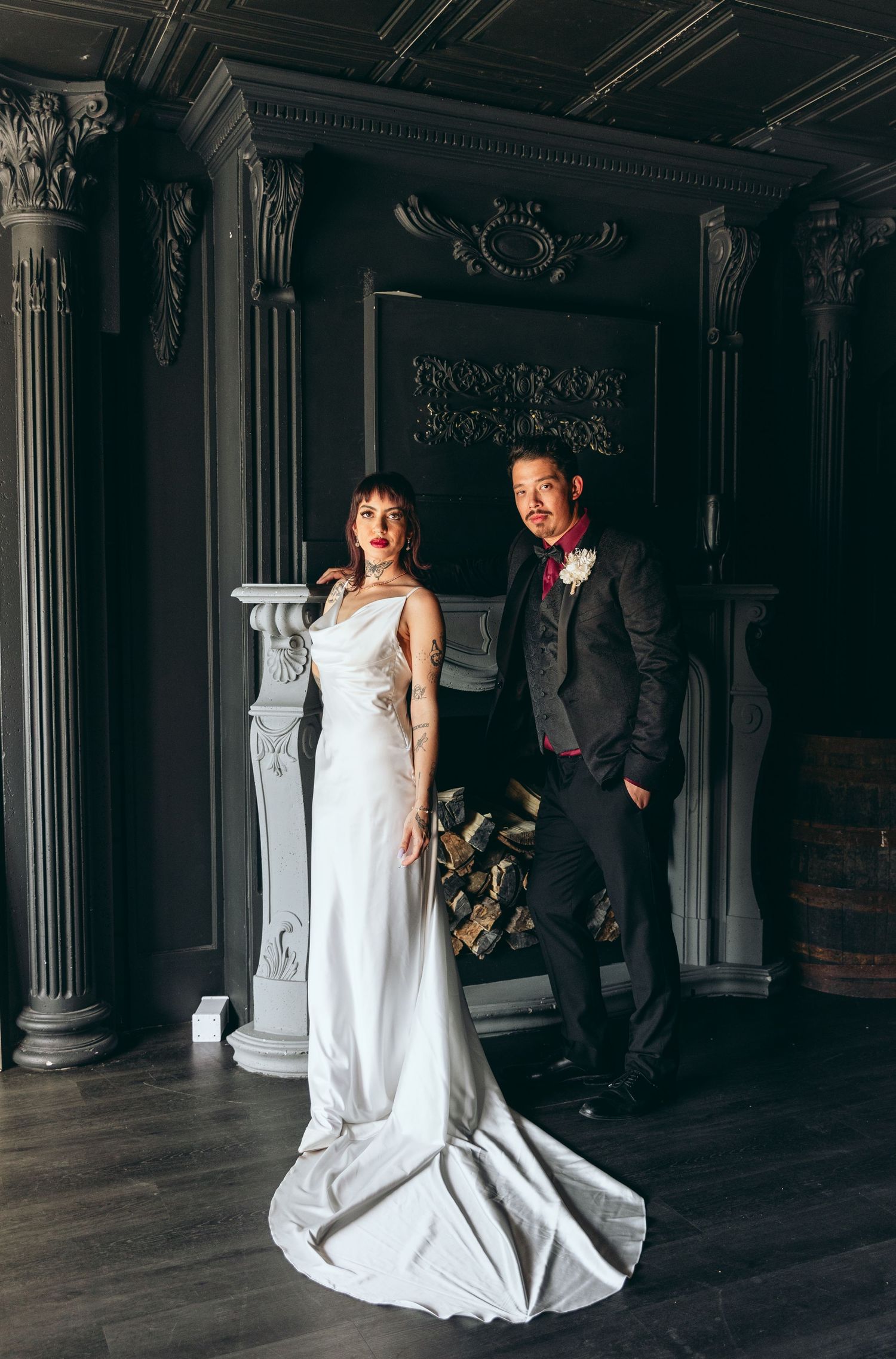 A dramatic wedding portrait in a dark vintage room with ornate architectural columns.