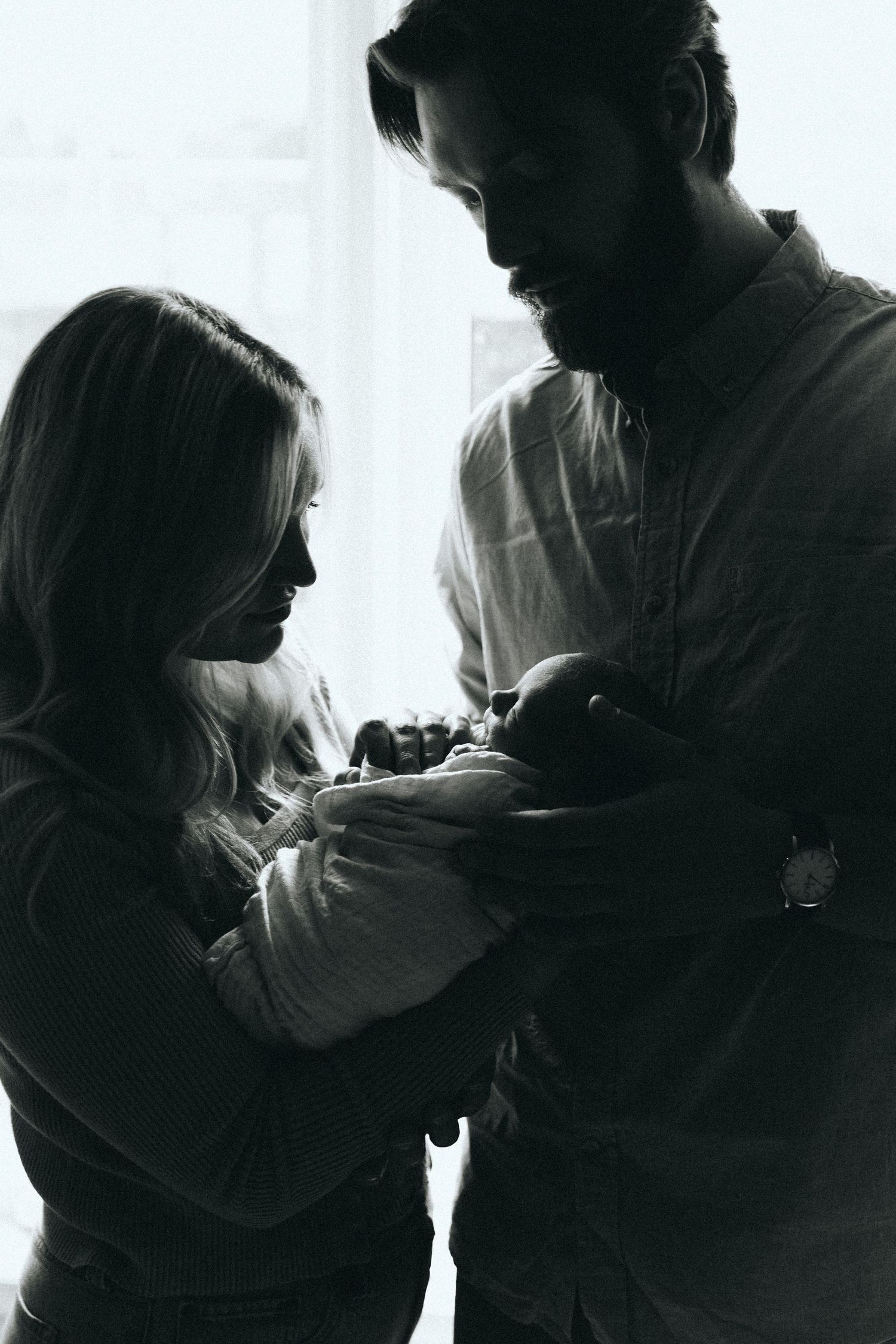 Silhouette series of intimate family moments against bright window.