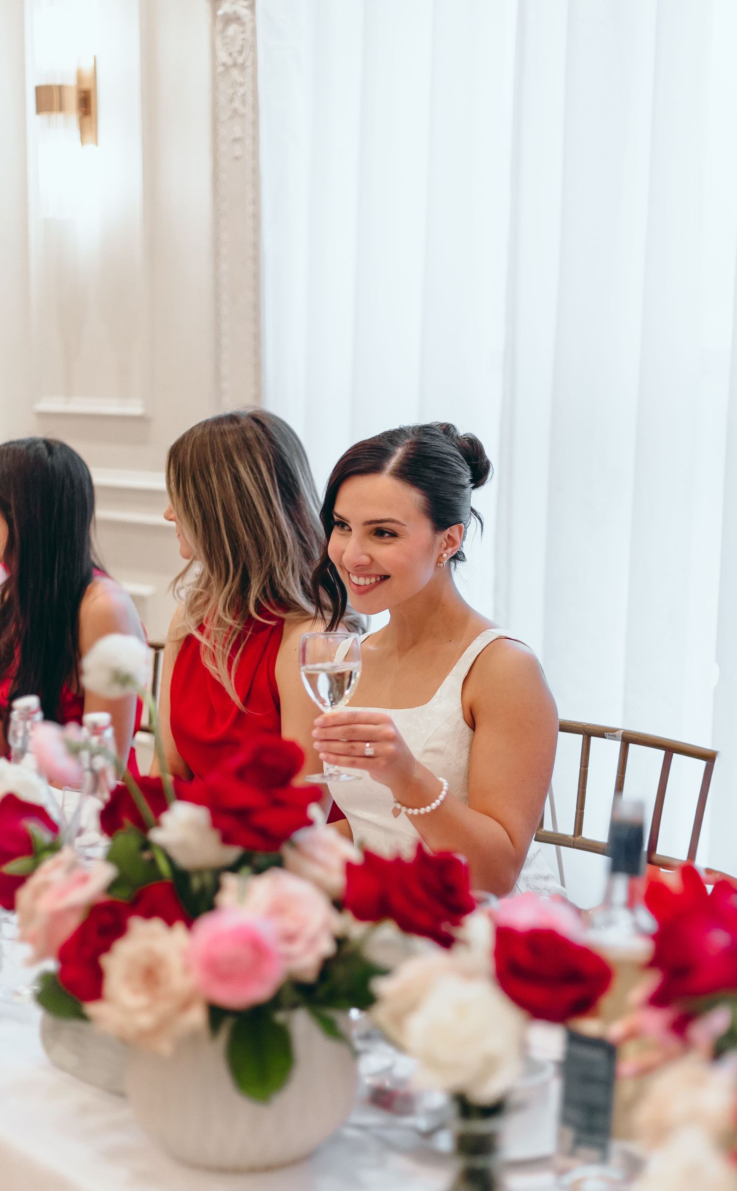 Elegant table setting with pink and red floral centerpieces and white linens.