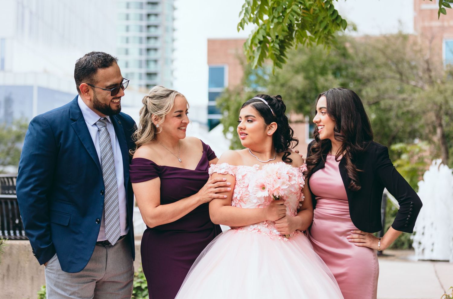 A group celebrates in formal attire with a pink ballgown as the centerpiece of their joyful gathering.