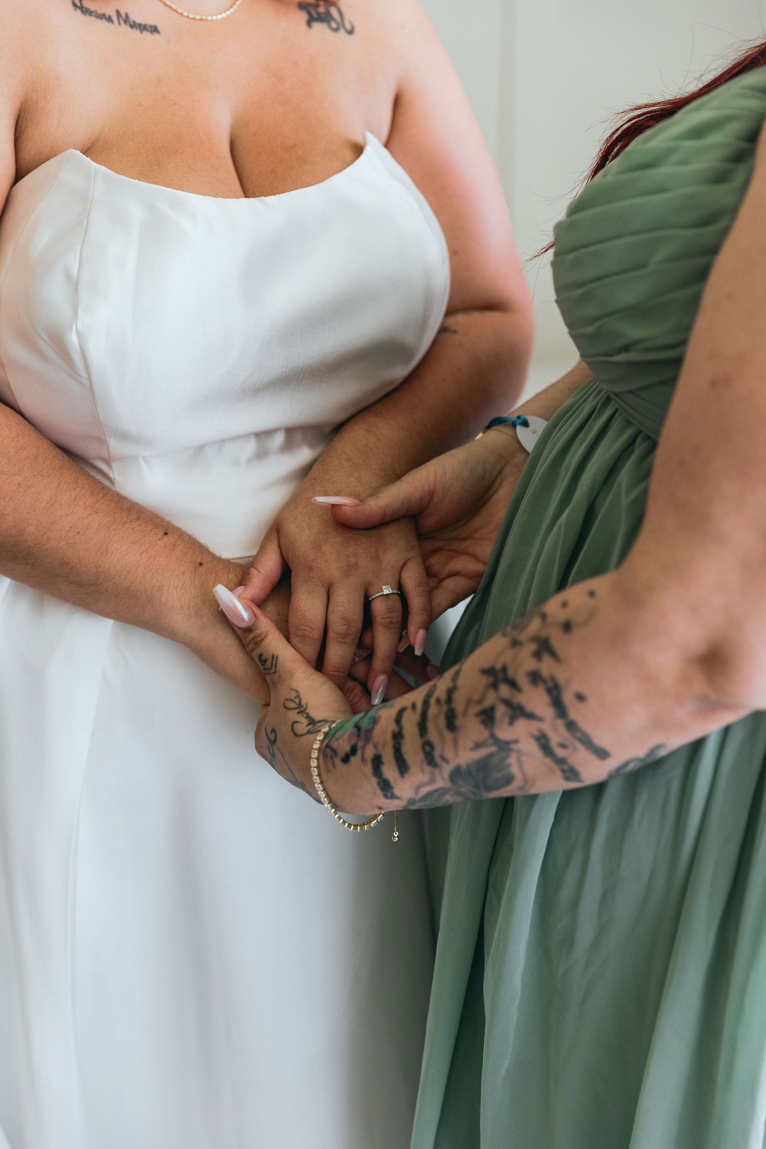 Close-up shots of wedding party members holding hands showing tattoos and dresses in sage green and white.
