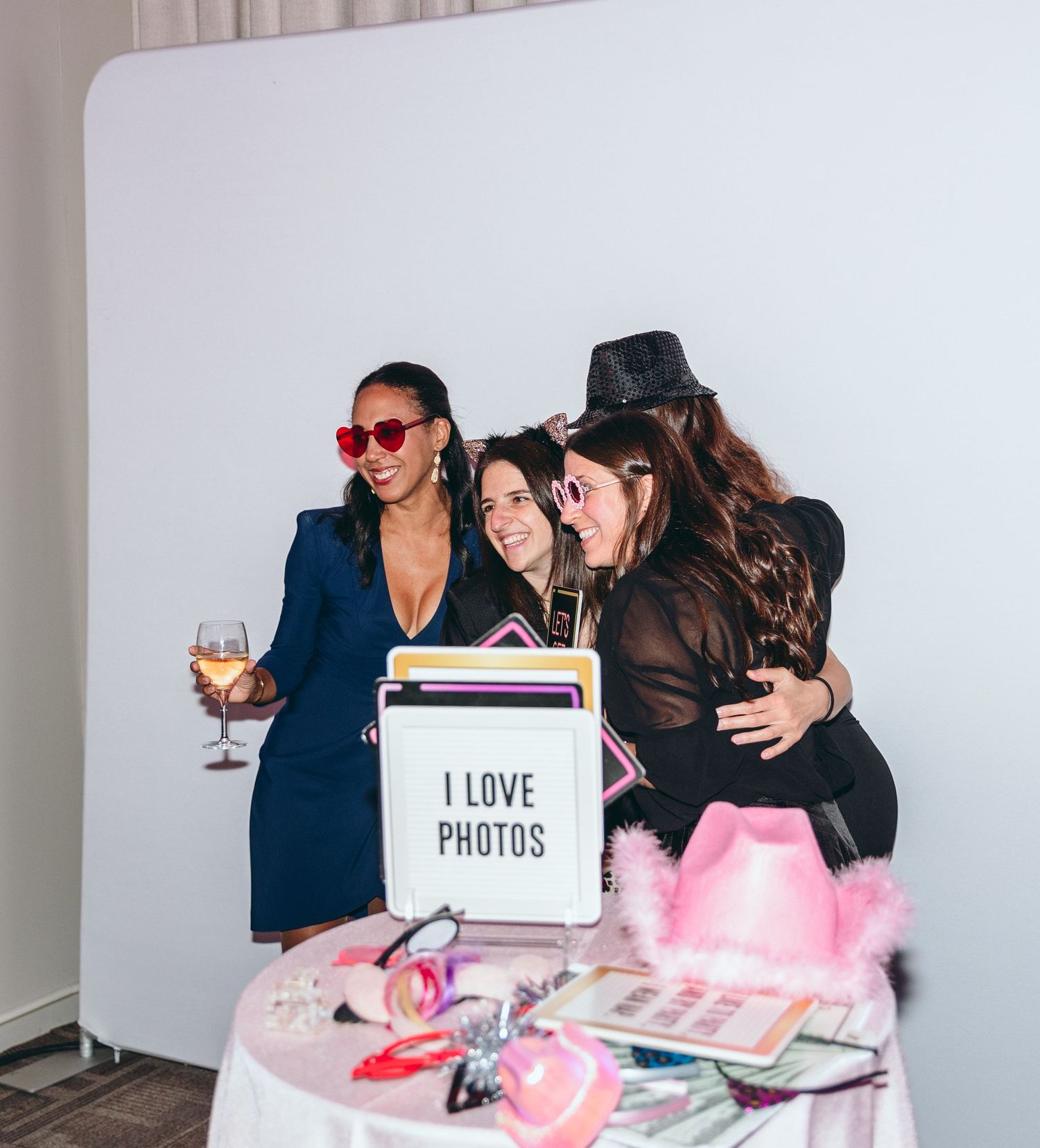 Photo booth setup at wedding reception with pink decor and props.