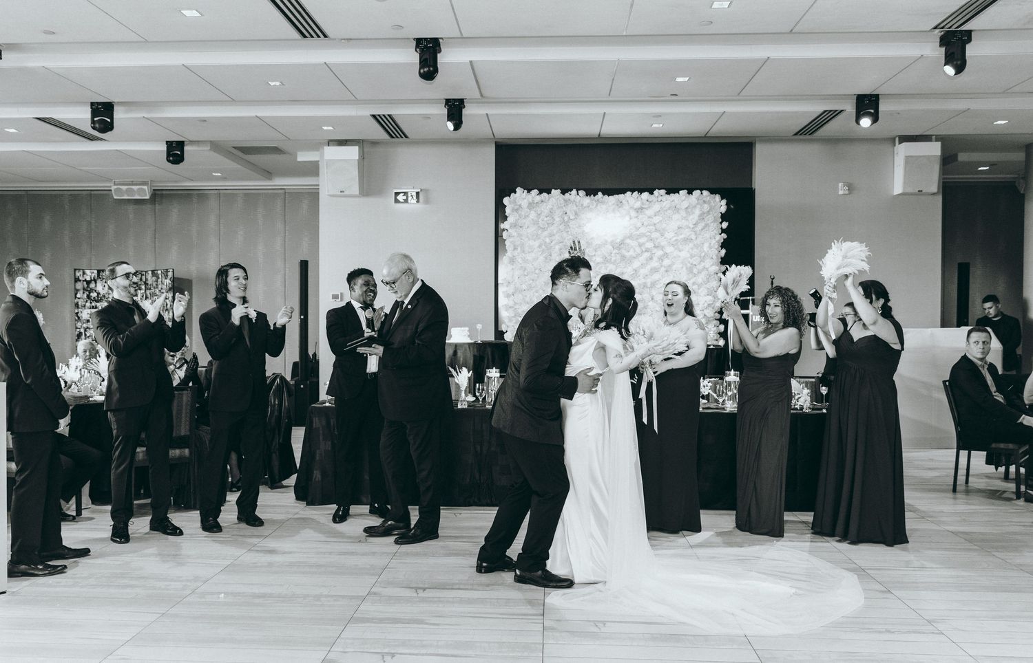 Black and white panoramic view of wedding guests gathered in a modern reception space.