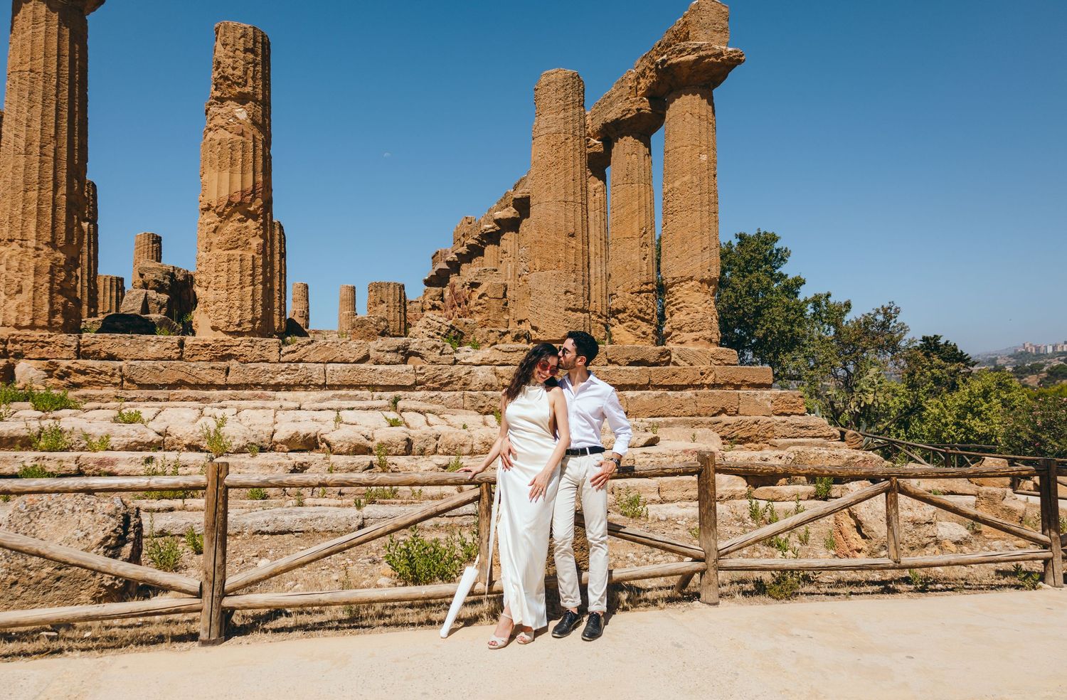 Ancient temple ruins with tall Doric columns stand against bright blue sky in Sicily's Valley of Temples.
