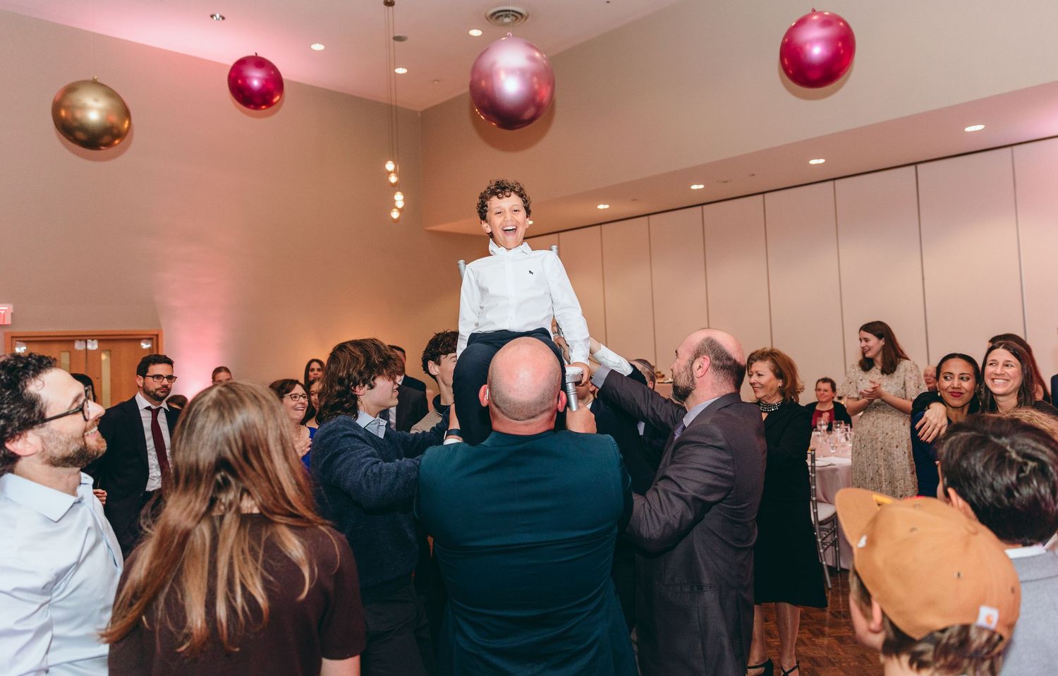 Wedding reception venue with pink ambient lighting and guests mingling.