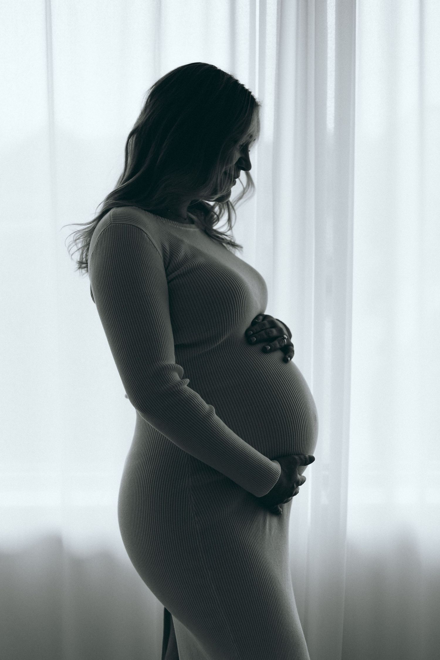 Silhouette maternity photos showing pregnancy progression against bright window.