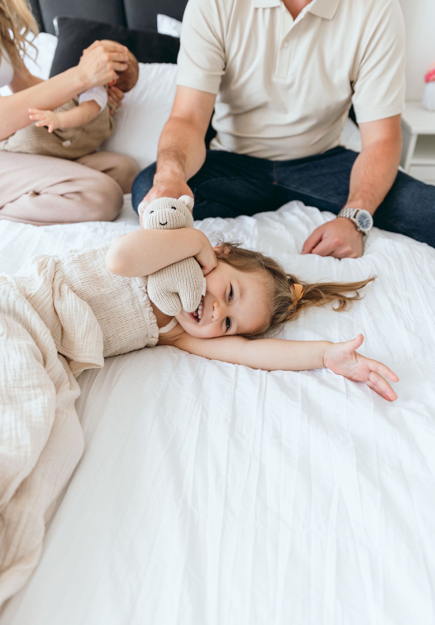 A couple lying on white bedding sharing an intimate moment together.