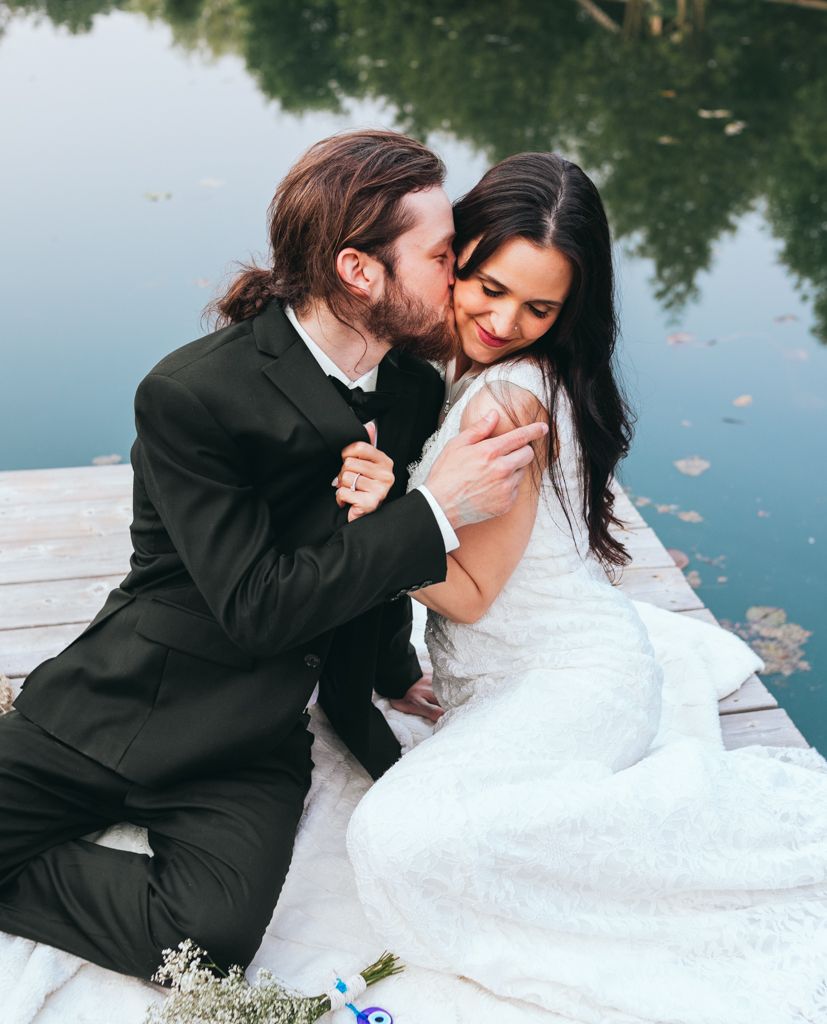 Romantic moment captured on dock as couple embraces during lakeside wedding shoot.