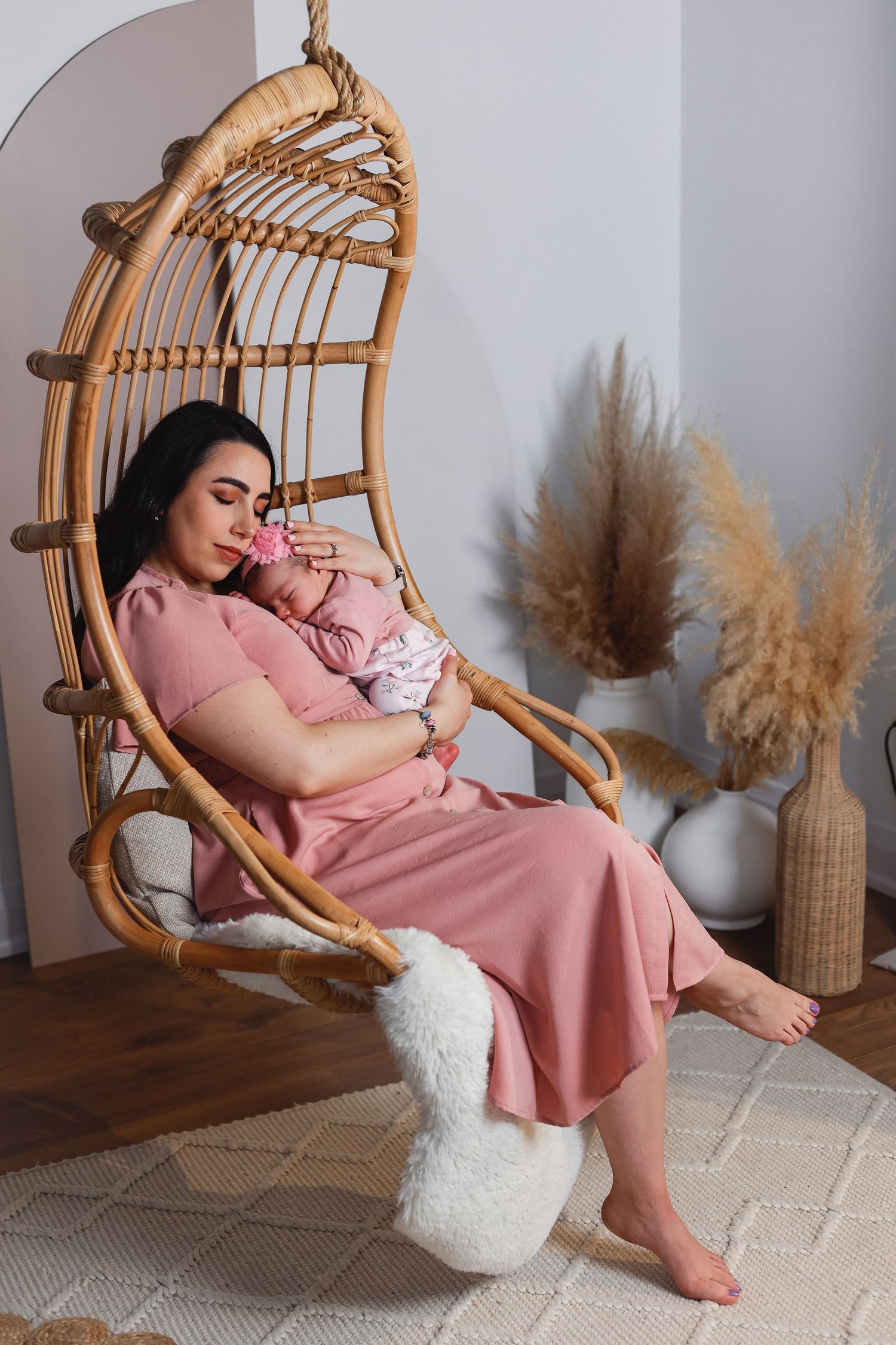 Peaceful moment in hanging rattan chair with pampas grass decor in background.
