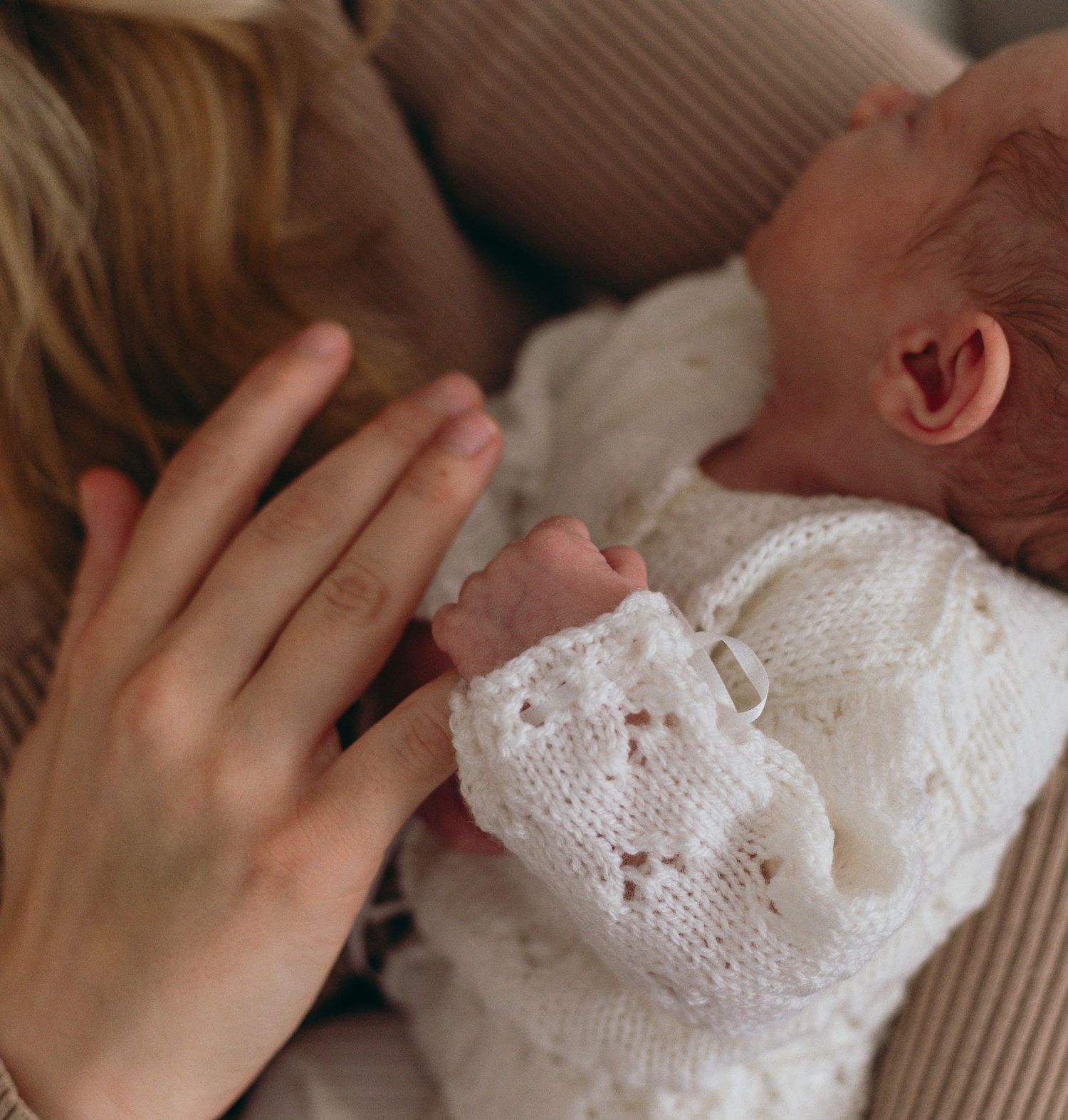 Close-up details of gentle hands touching soft knit fabric in warm lighting.