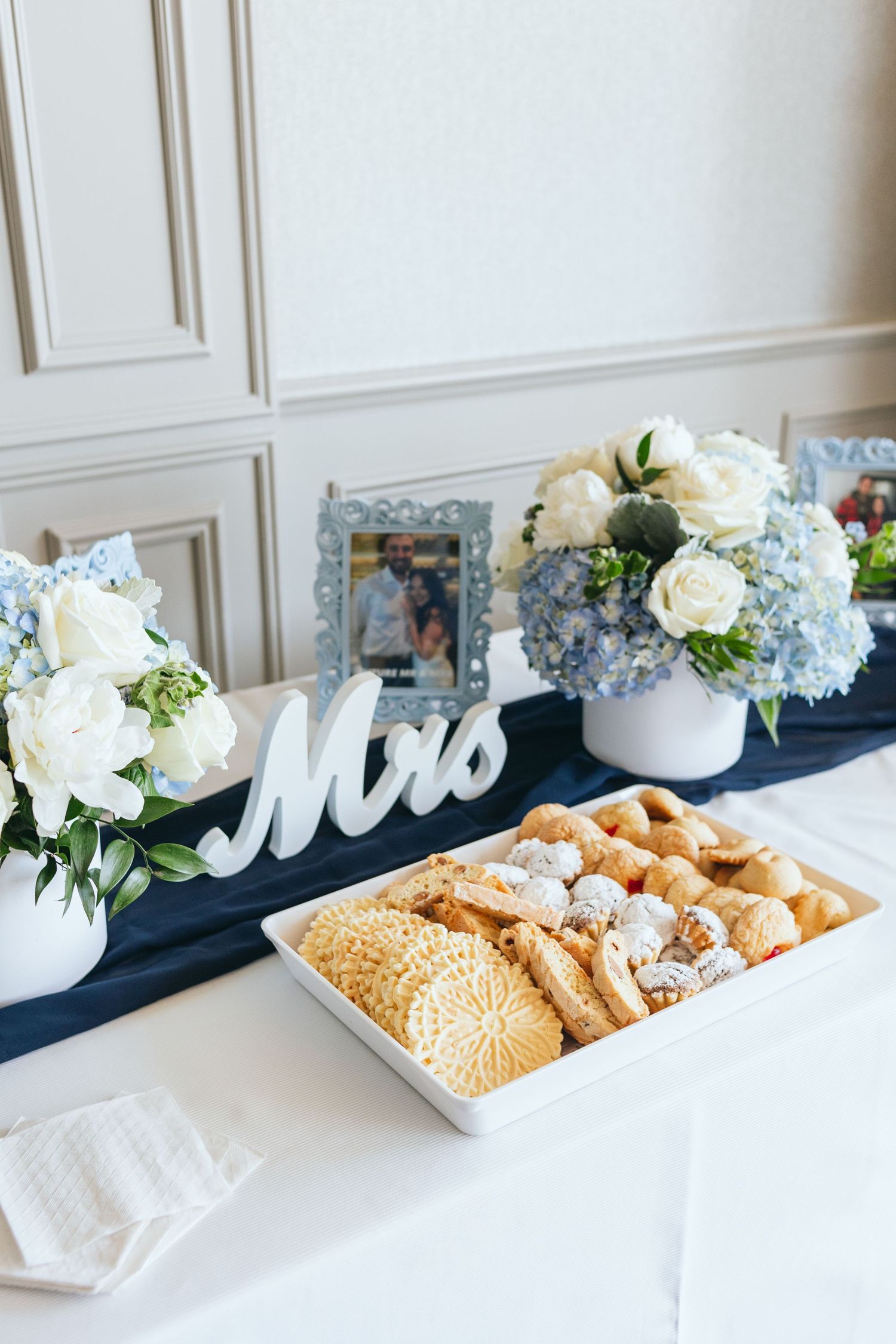 White floral arrangements and refreshments displayed on a table with navy blue accents.
