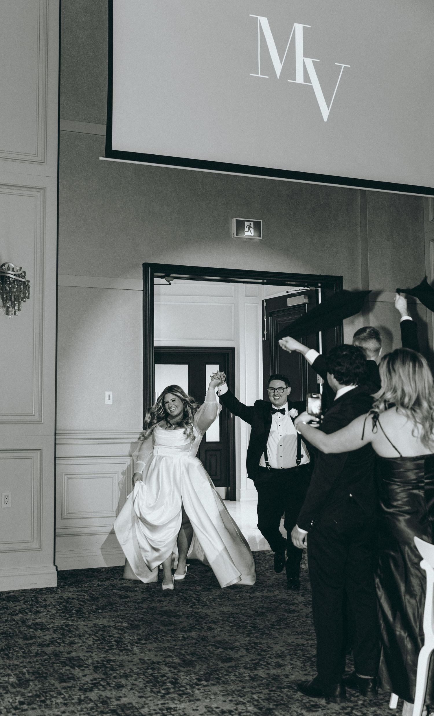 Grand entrance celebration with guests cheering at formal event.