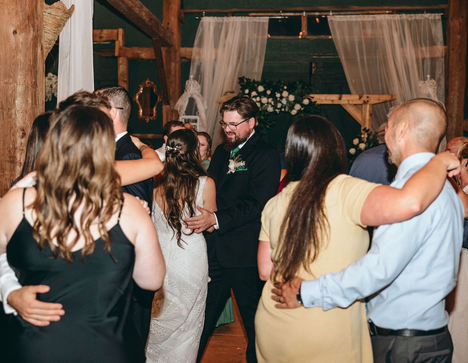 Wedding guests dancing in pairs during reception celebration in rustic venue.
