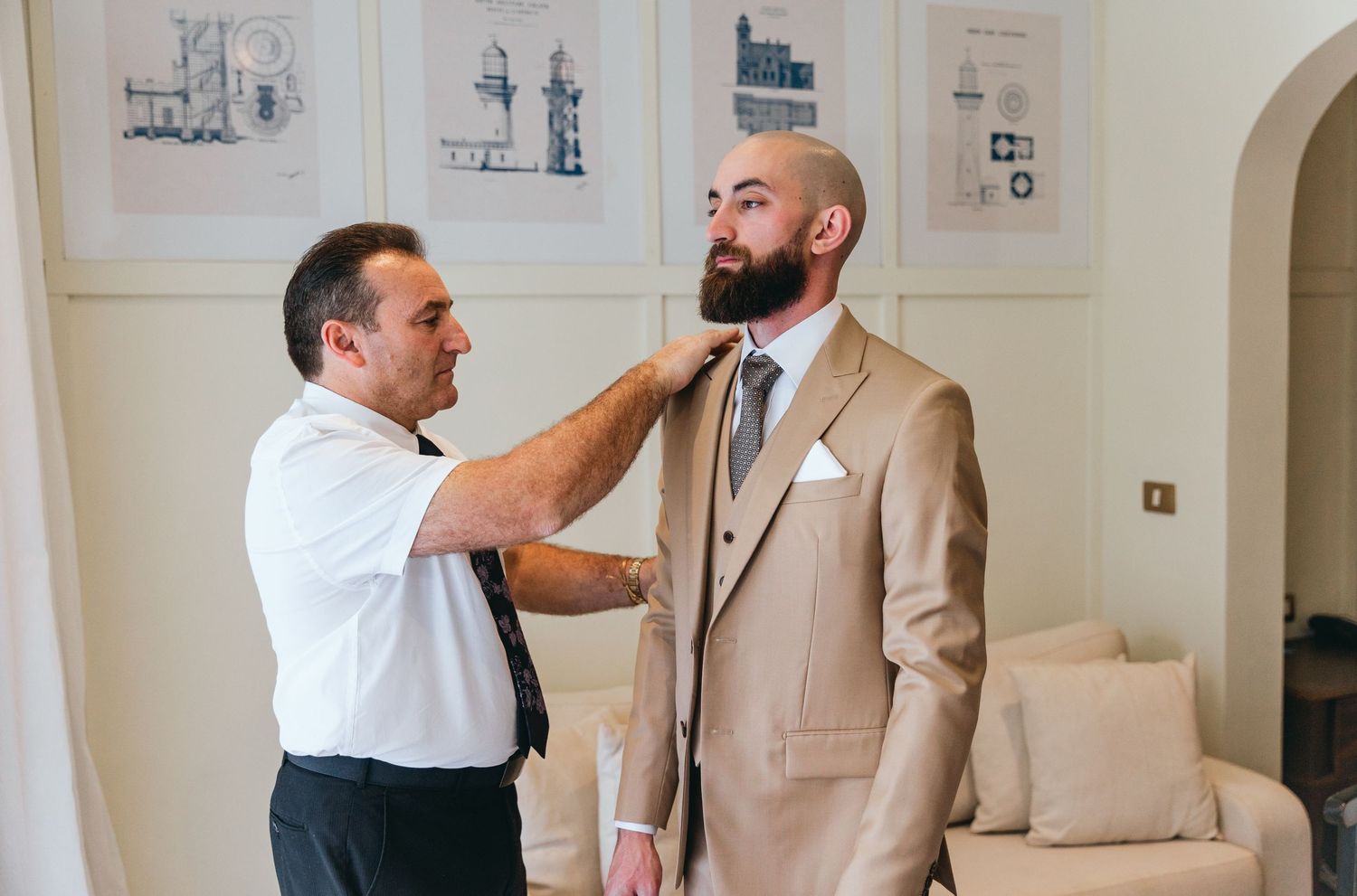 Men in formal attire share animated conversation in bright room with framed wall art.