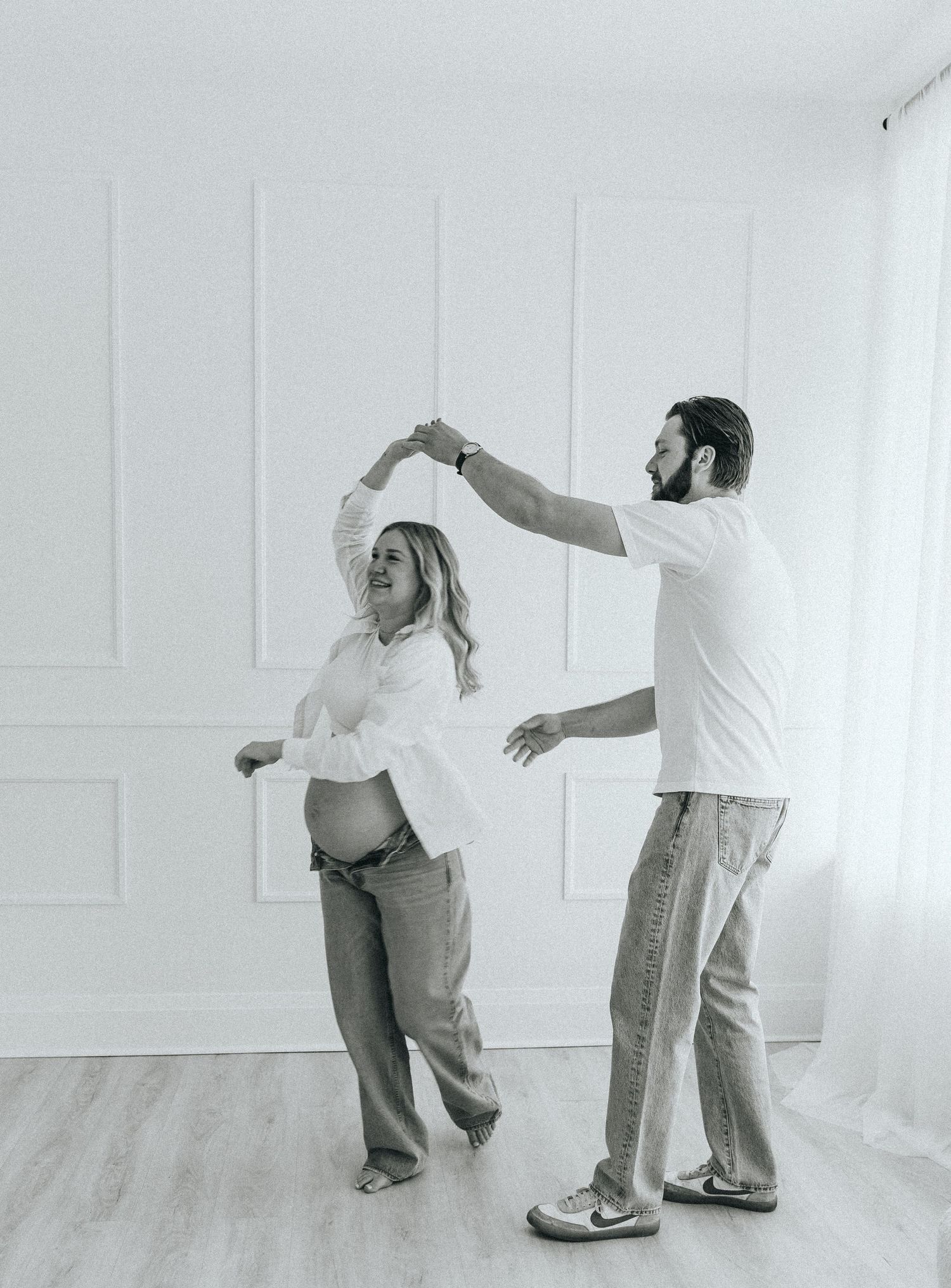 Dancing sequence of expectant couple showing joyful movements in bright studio.