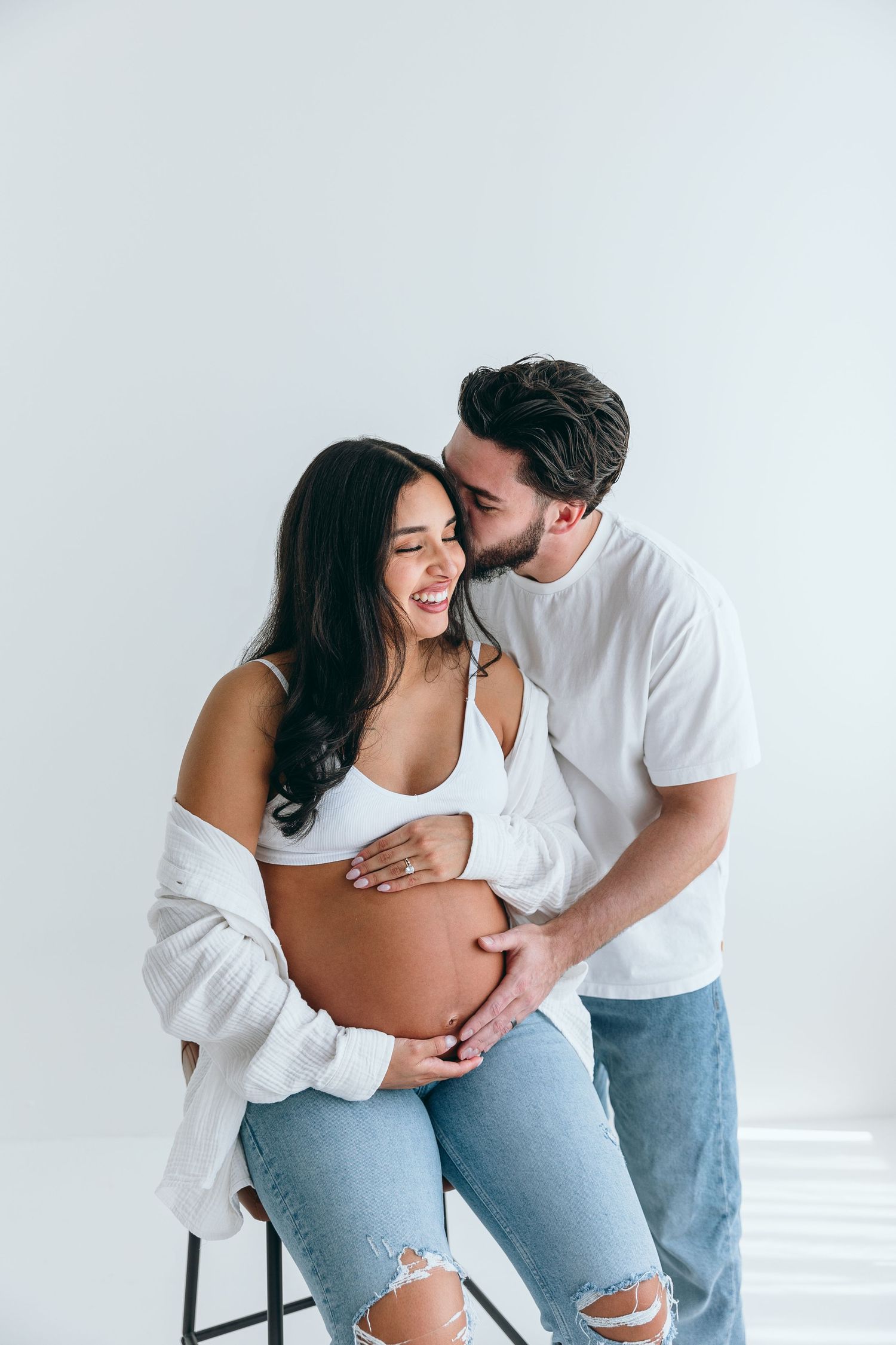 Intimate maternity portrait of couple sharing tender moment in studio setting.